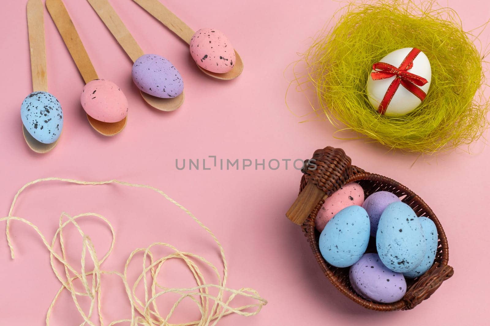 Colored Easter eggs on wooden spoons and in a wicker basket with a nest. by mvg6894