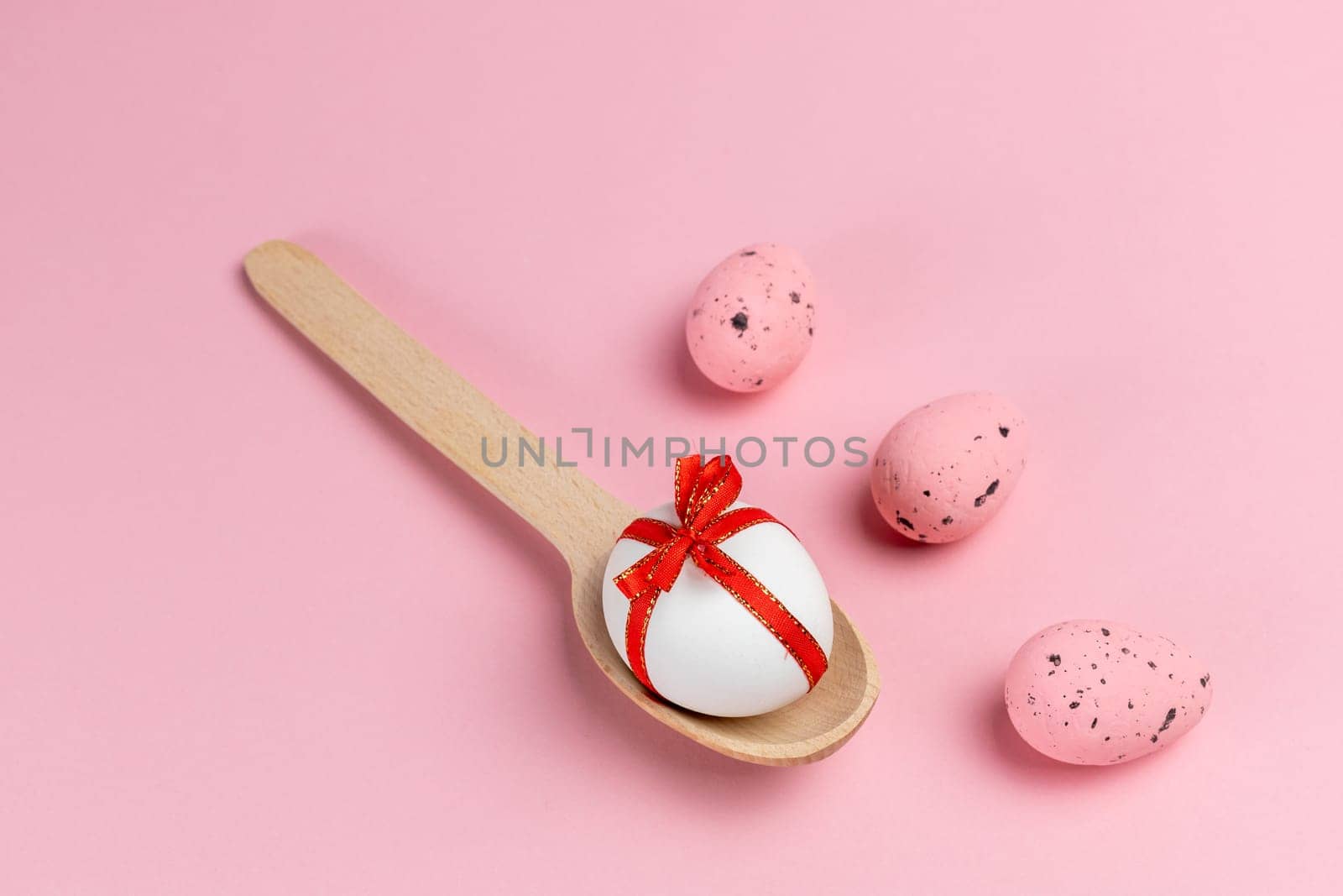 Colored Easter eggs with the wooden spoon on the pink background. Top view.