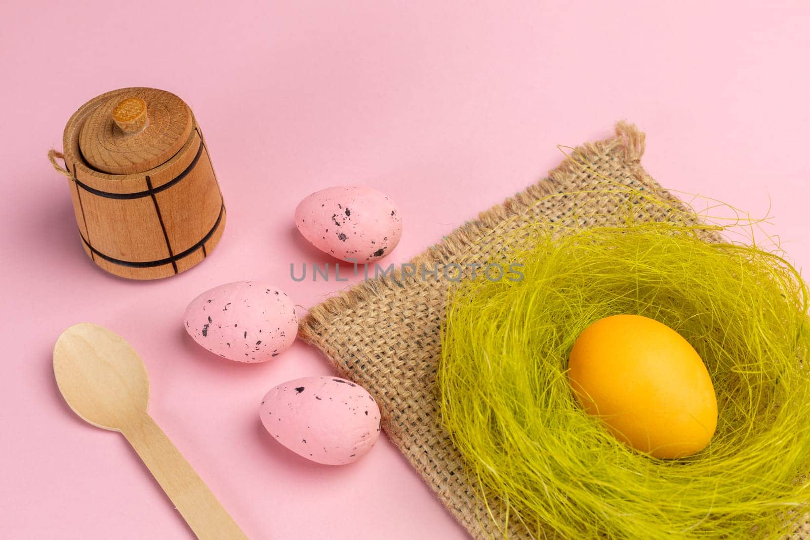 Colored Easter eggs and wooden utensils and cutlery with the pink background. Top view.