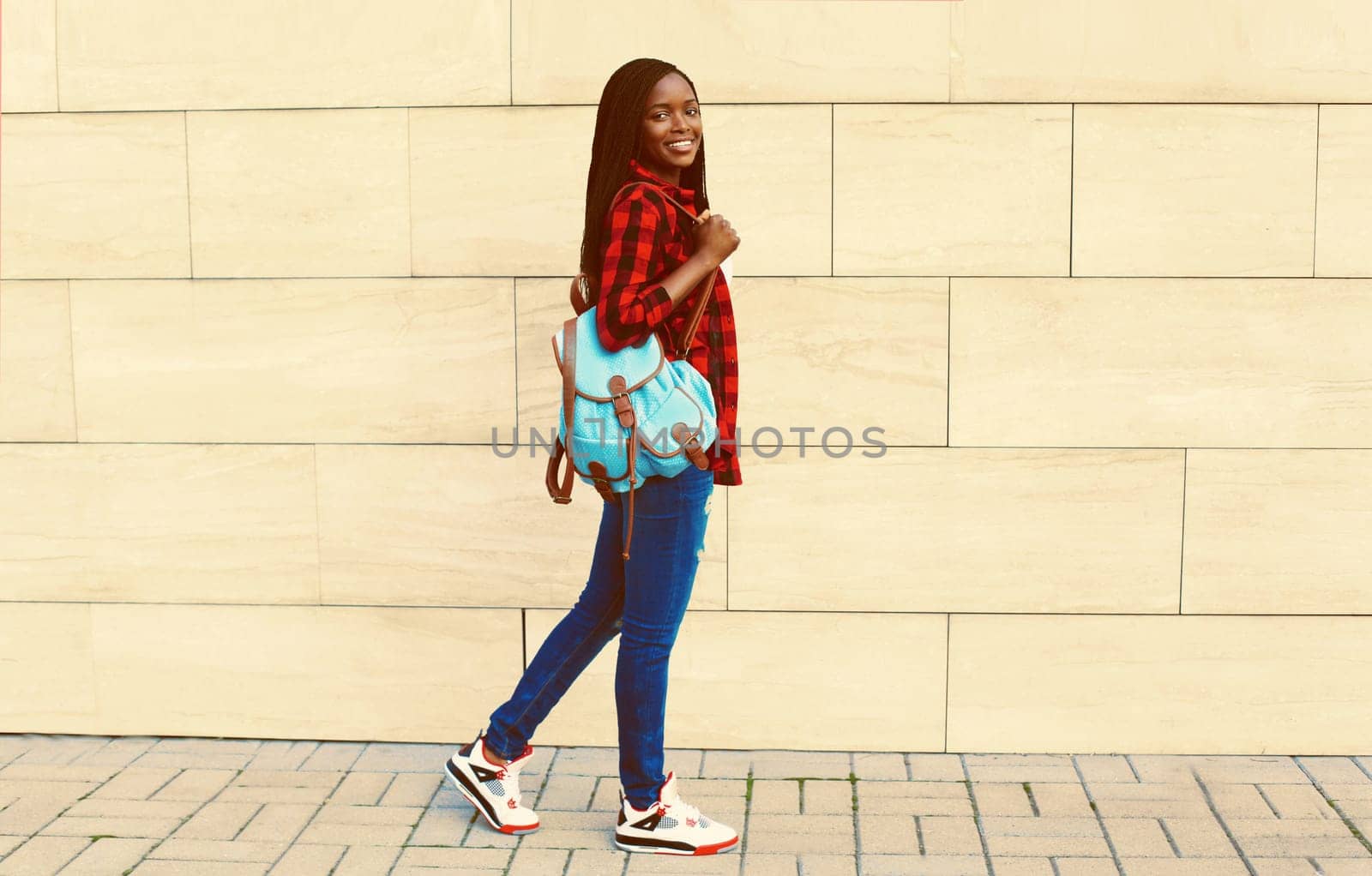 Portrait of young african woman with backpack on the city street by Rohappy
