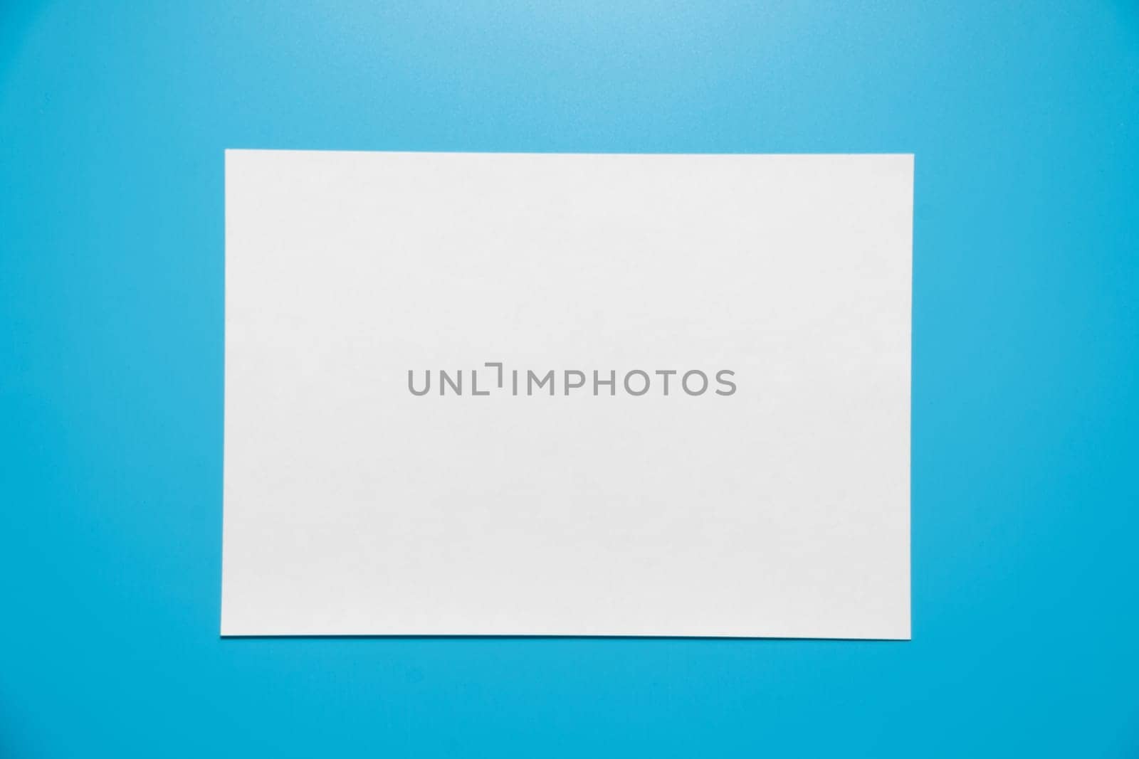 Empty white paper sheet isolated on blue background..