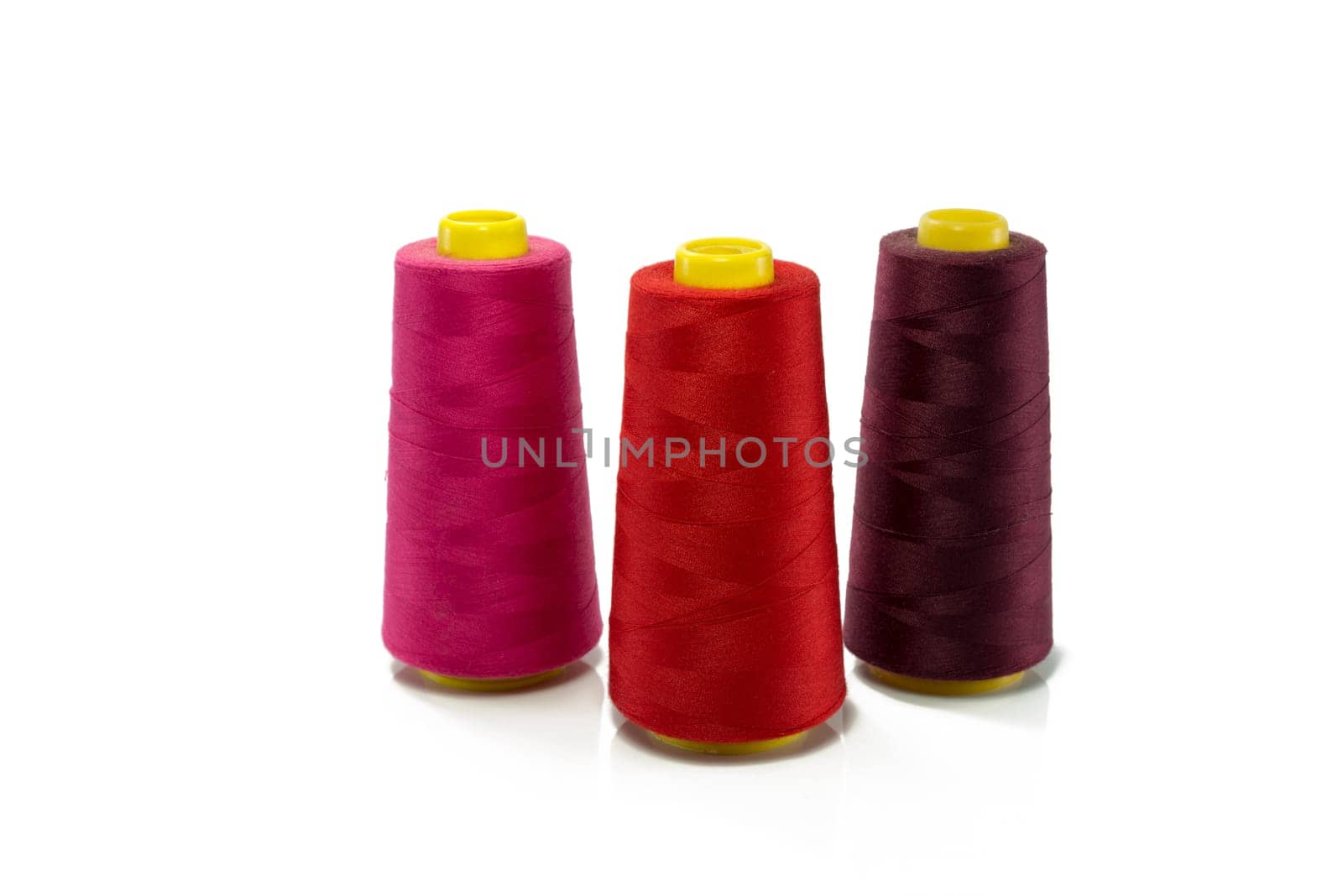 spool with red orange and purple thread for sewing machine isolated on white background
