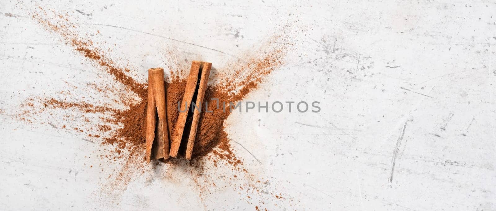 Closeup detail - cinnamon bark and milled powder on white stone board, view from above, space for text right side by Ivanko