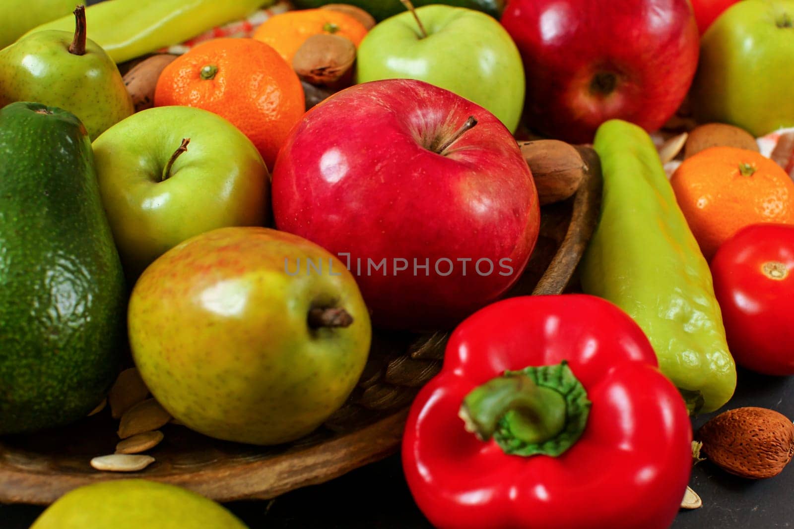 Mixed fruit - apples, pears, tangerines; and vegetable - peppers, tomatoes, avocados; with some whole almonds and nuts, closeup photo by Ivanko