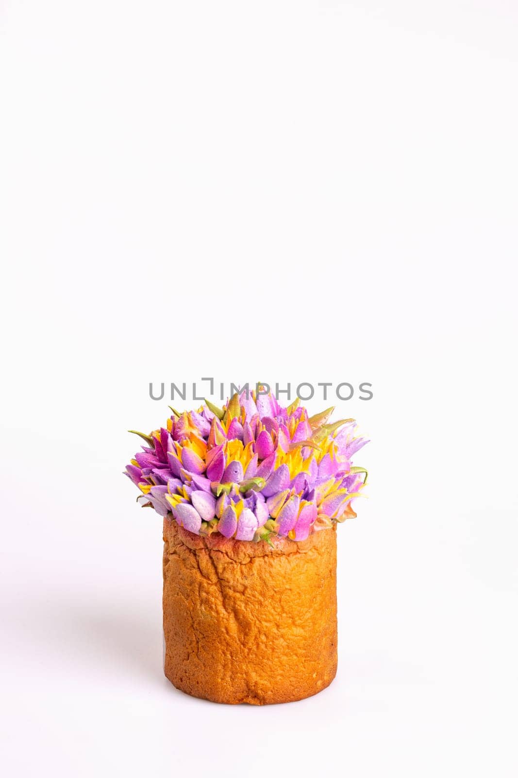 Loaf of bread decorated with a colorful variety of tulips sits on a white surface with a white background.