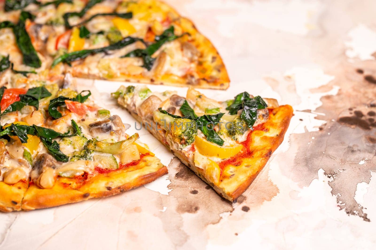 Vegetarian pizza slice with broccoli, peppers and spinach on white table by Pukhovskiy