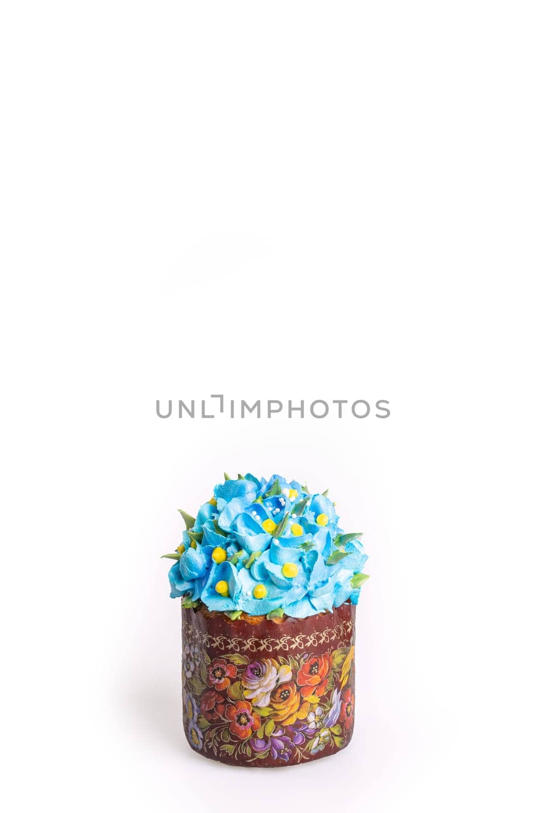 A small round cake with blue icing and delicate flower decorations on a white surface, featuring a golden brown base.