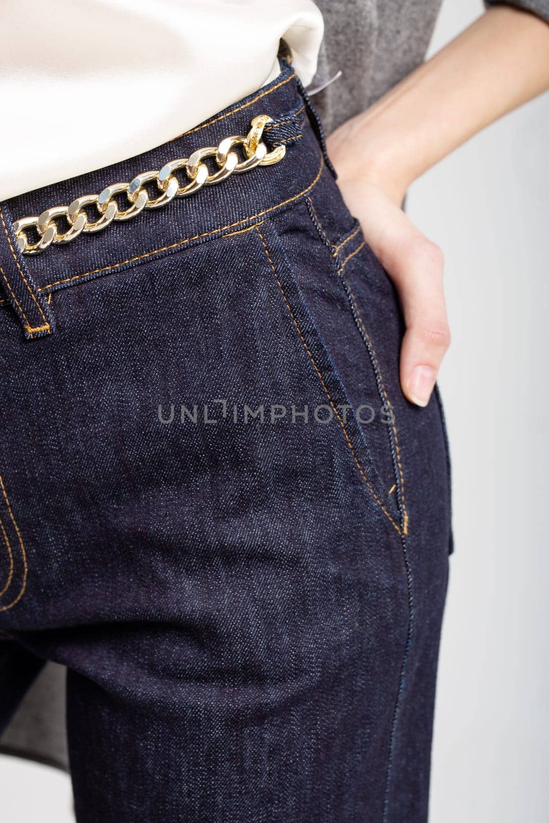 Chic dark blue jeans with a trendy gold chain belt. High-waisted, slim fit design for a touch of luxury and style.