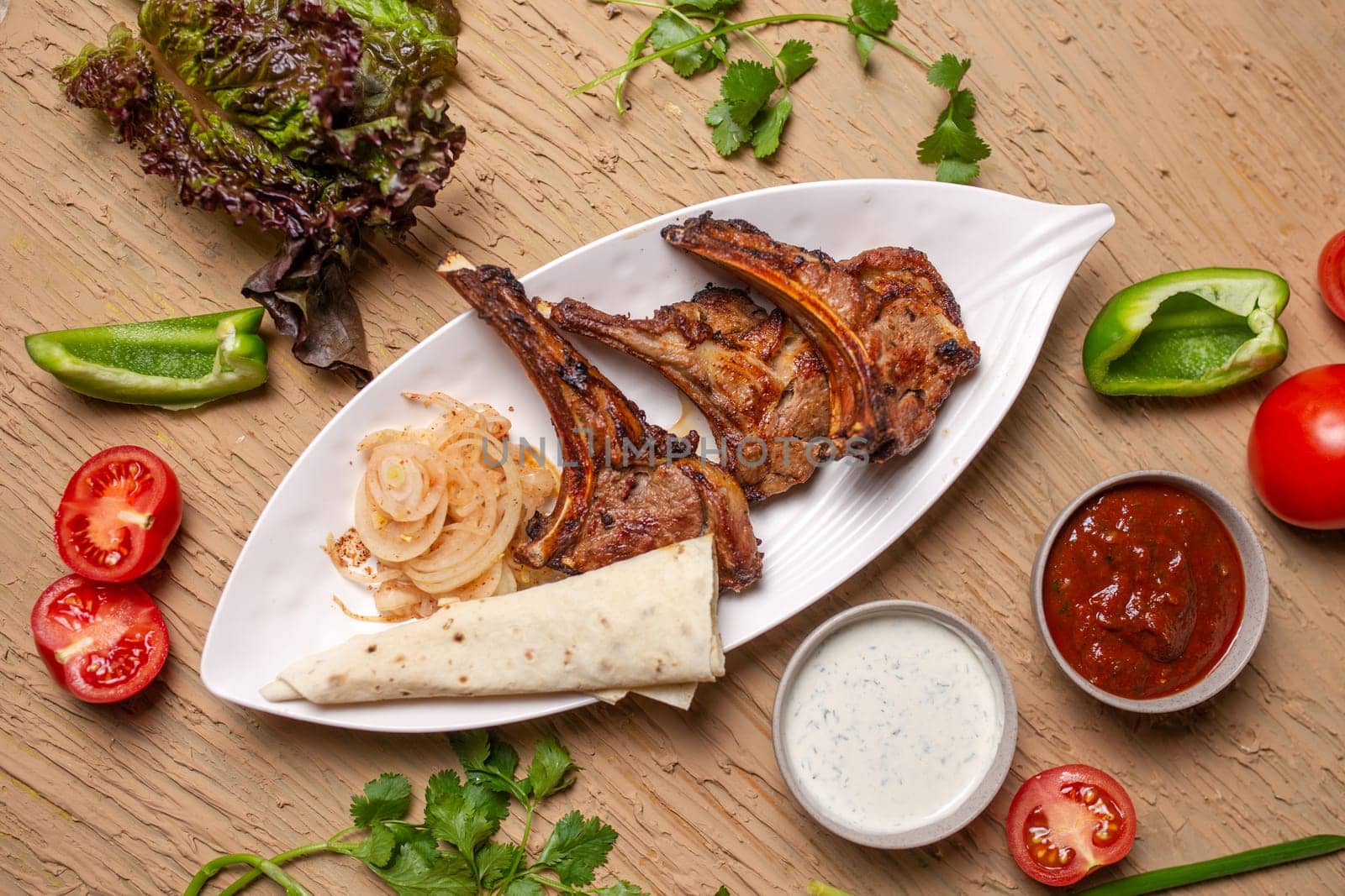 Top view Grilled lamb chops with vegetables and lavash bread on a wooden table by Pukhovskiy