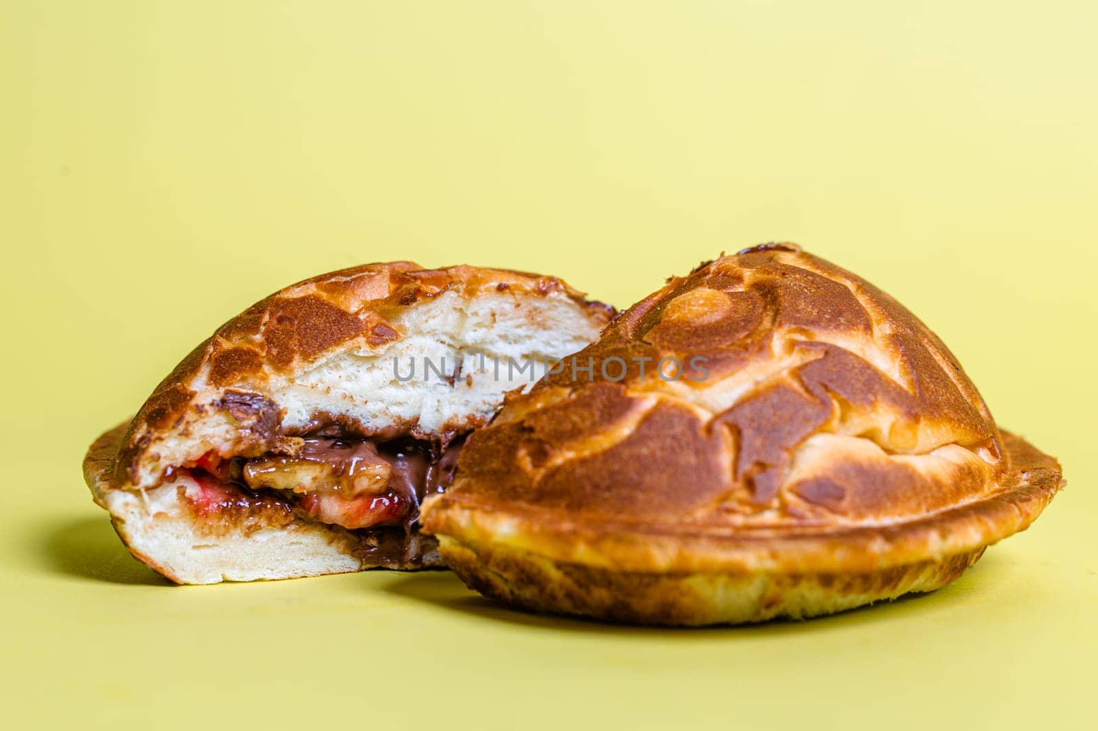 a closed cut burger with juicy filling on a yellow background.
