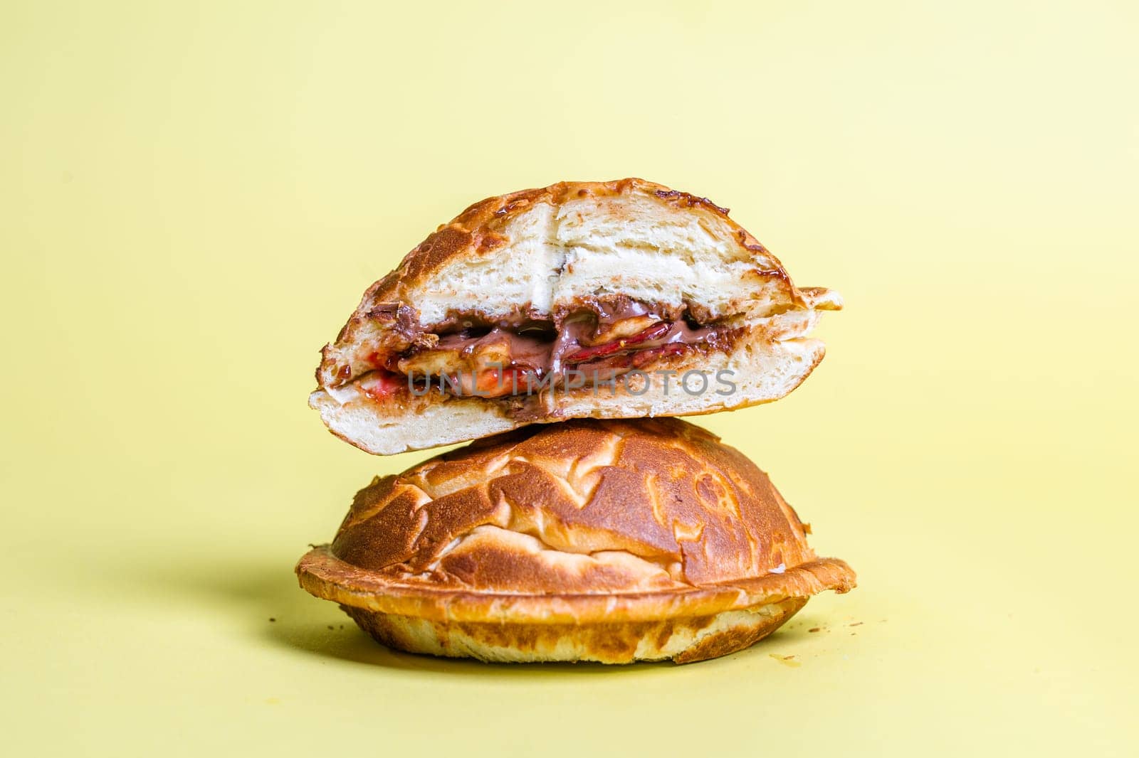 a closed cut burger with juicy filling on a yellow background.