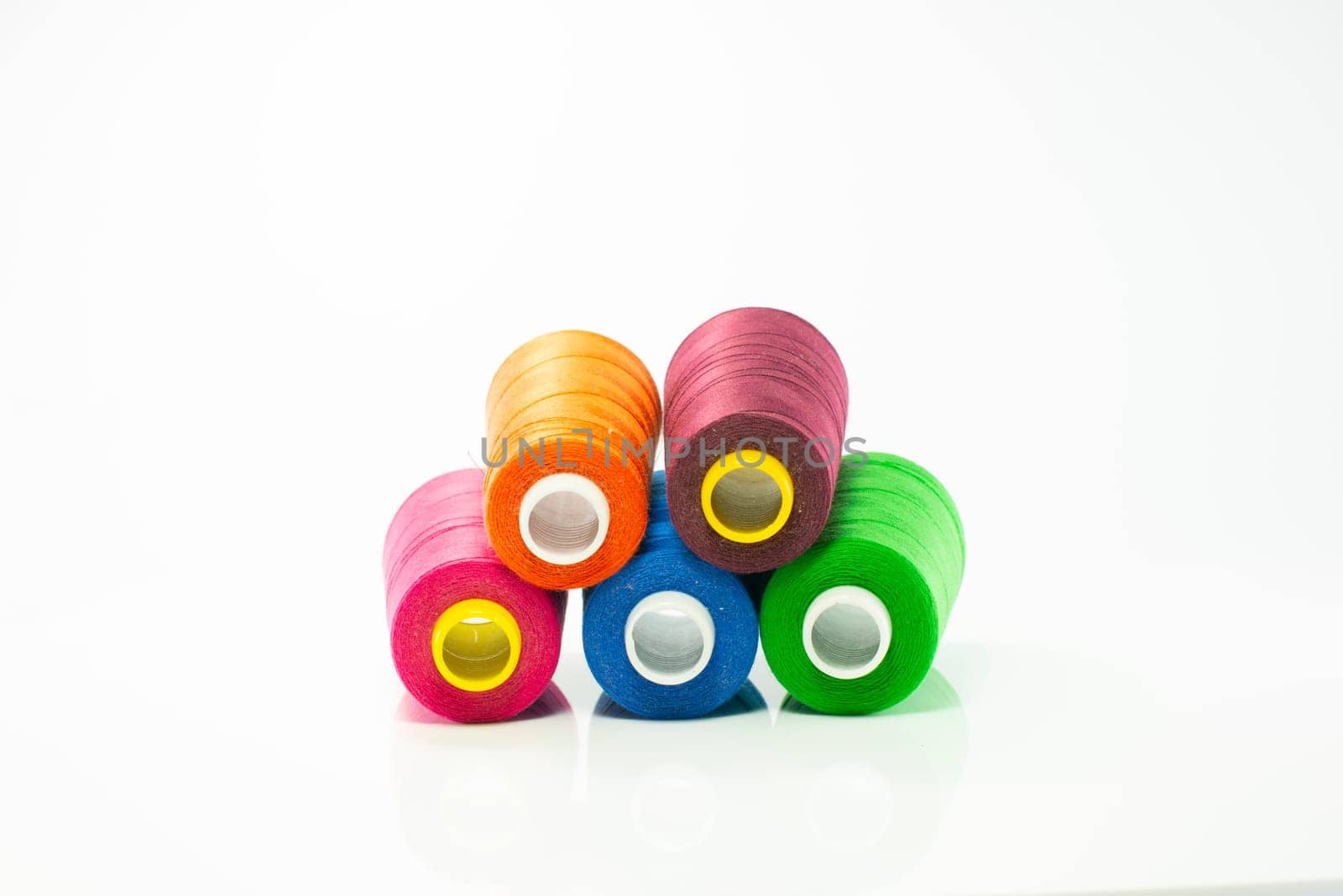spool with red orange and purple thread for sewing machine by compuinfoto
