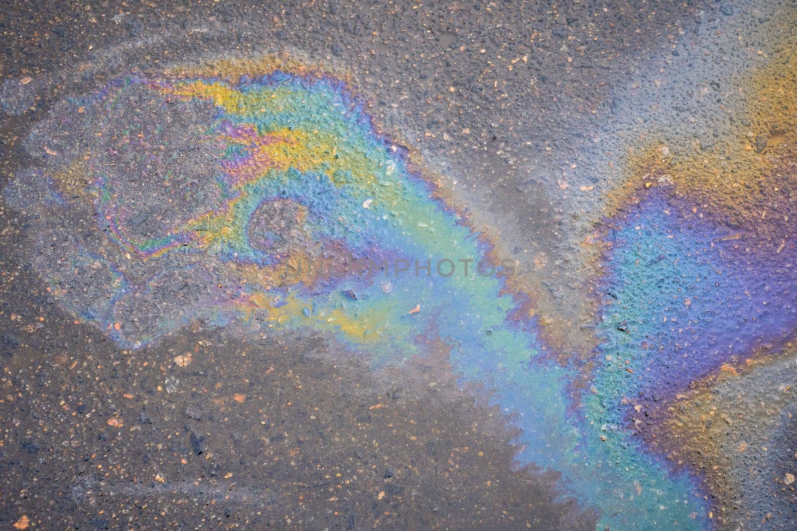 Textured stain of fuel or oil on wet asphalt on a rainy day. The concept of environmental pollution.