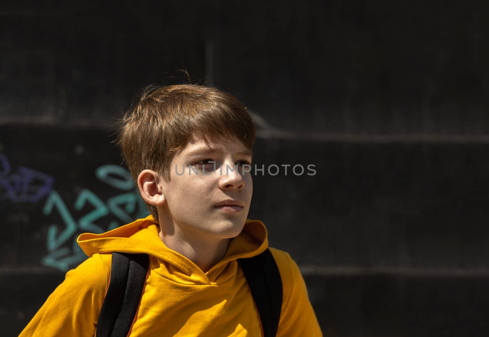 Urban teen or gen z portrait on the street. Dreamy boy in yellow hoodie.