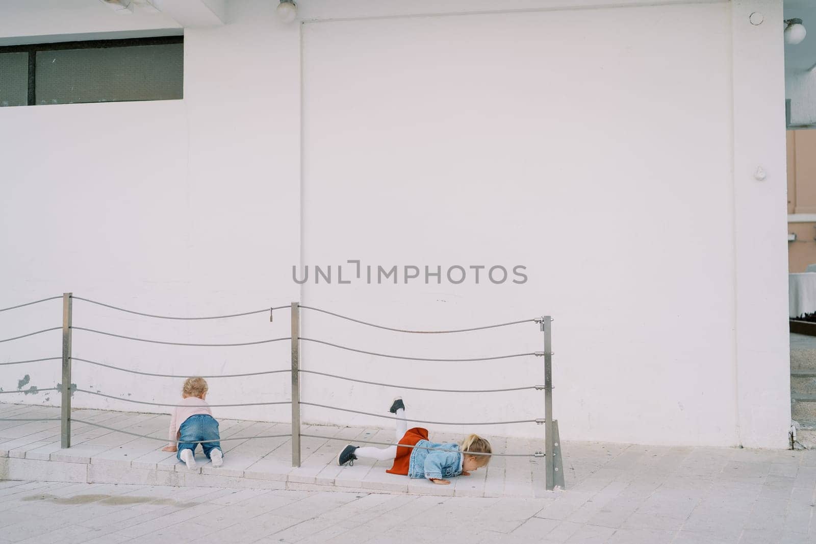 Little girls crawl on the ramp near the building. High quality photo