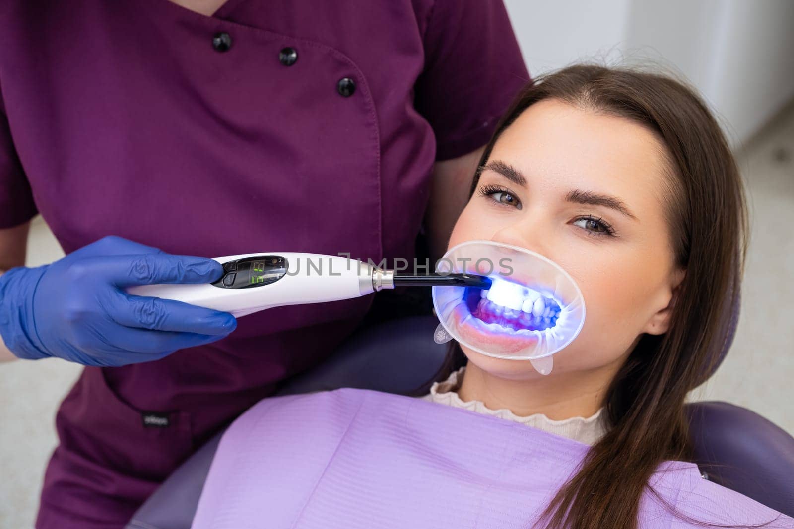 Dentist employs a UV lamp to cure the fillings in the patients teeth.