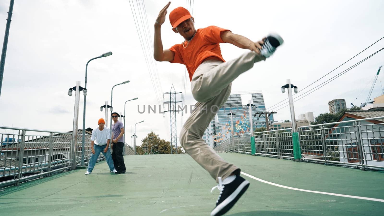 Young happy hipster perform break dancing or foot step with friend moving to hiphop music together. Skilled dancer doing freeze pose and waving hand. Modern lifestyle. Outdoor music 2024. Sprightly.