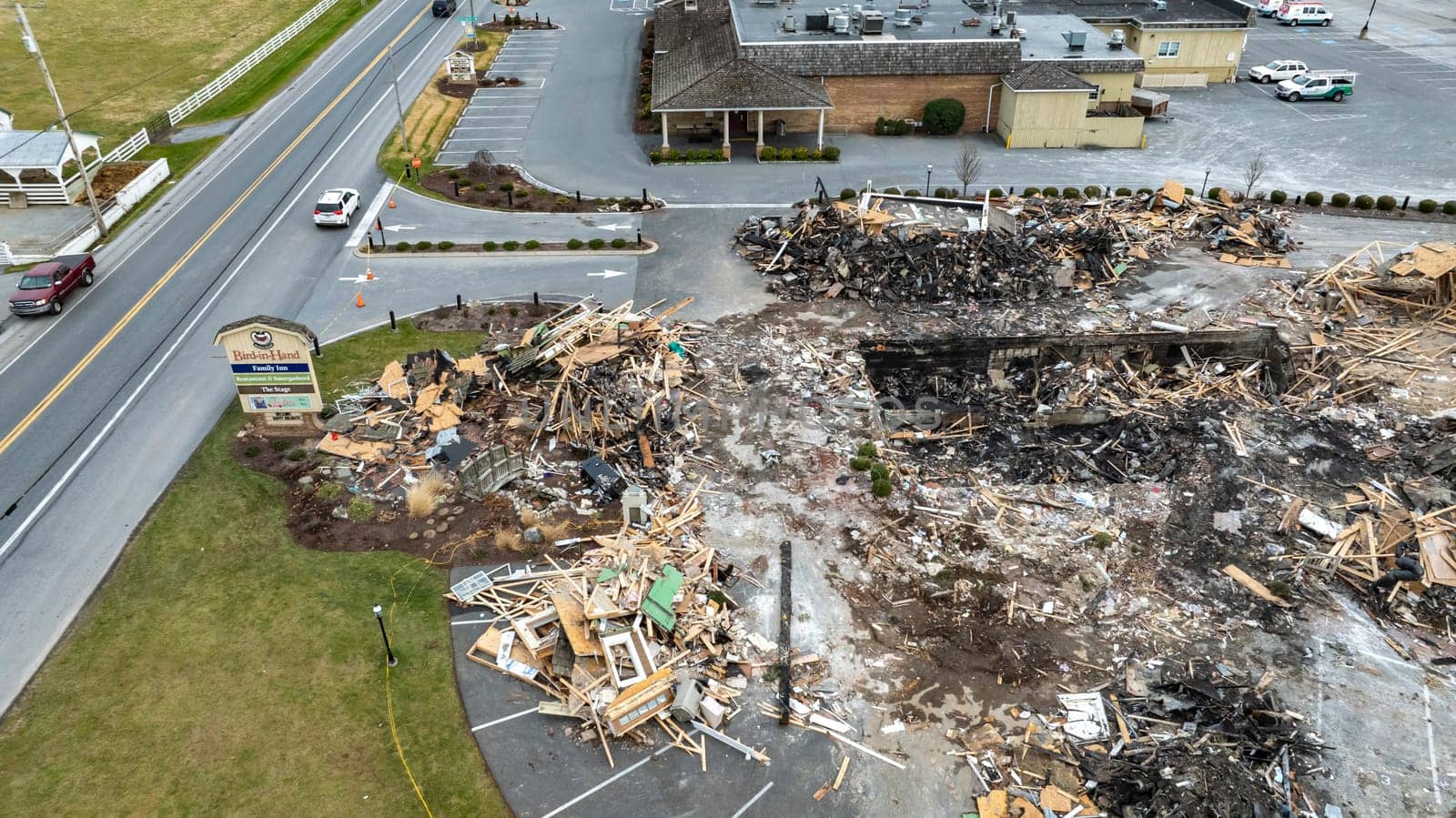 Bird in Hand, Pennsylvania, USA, September 14, 2023 - An Aerial View Of A Devastated Building Amidst Intact Structures With Cars On The Road And Green Fields In The Background Under A Cloudy Sky.