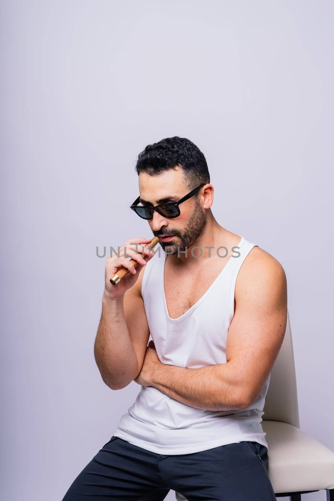Young man with beard smoking a cigar in studio by Zelenin