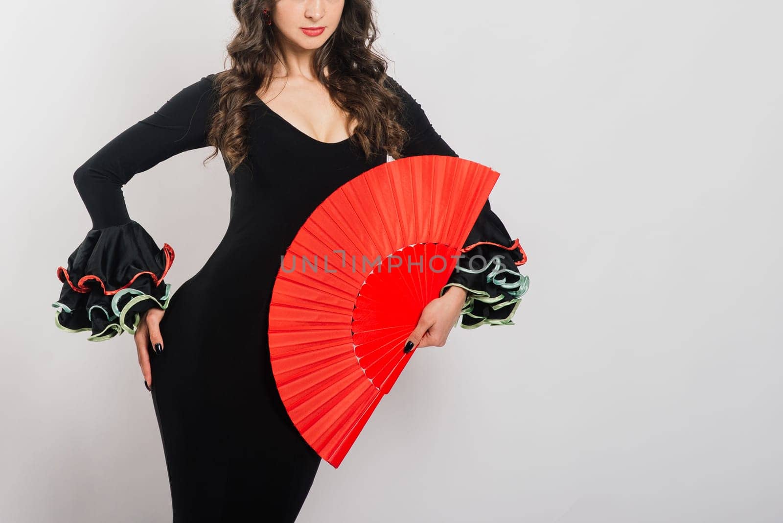 Portrait of beautiful young woman dancing flamenco with fan in studio