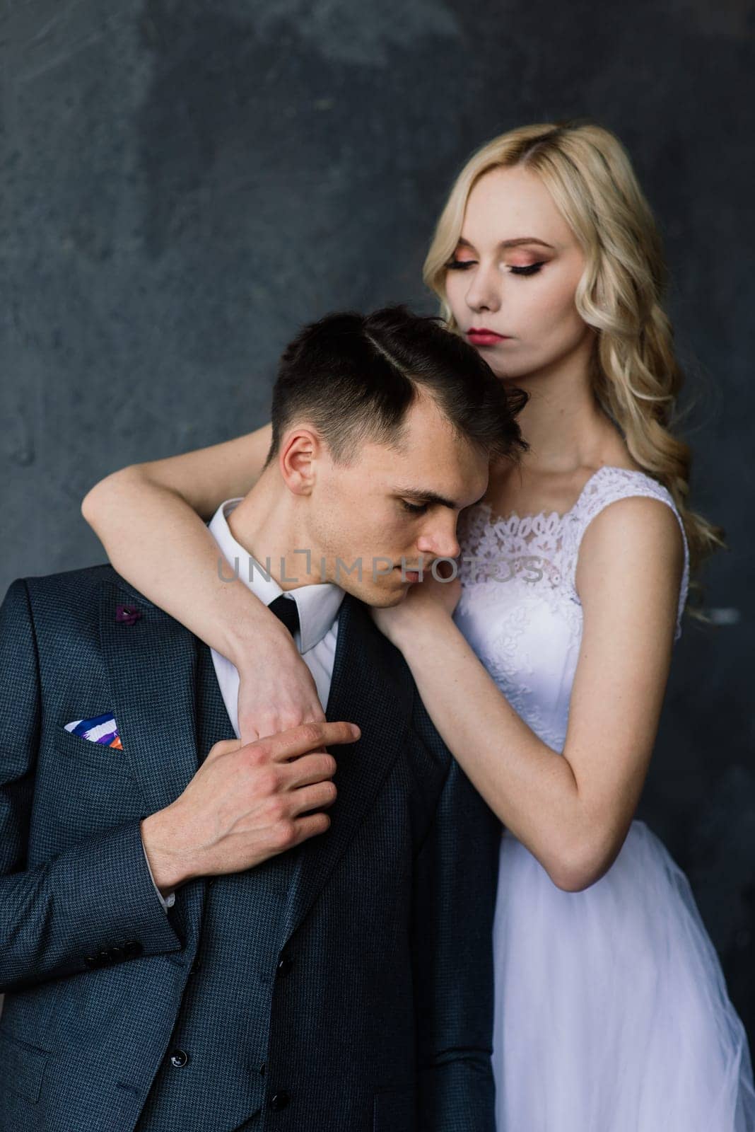 Cute wedding couple in the interior of a classic studio decorated. They kiss and hug each other.