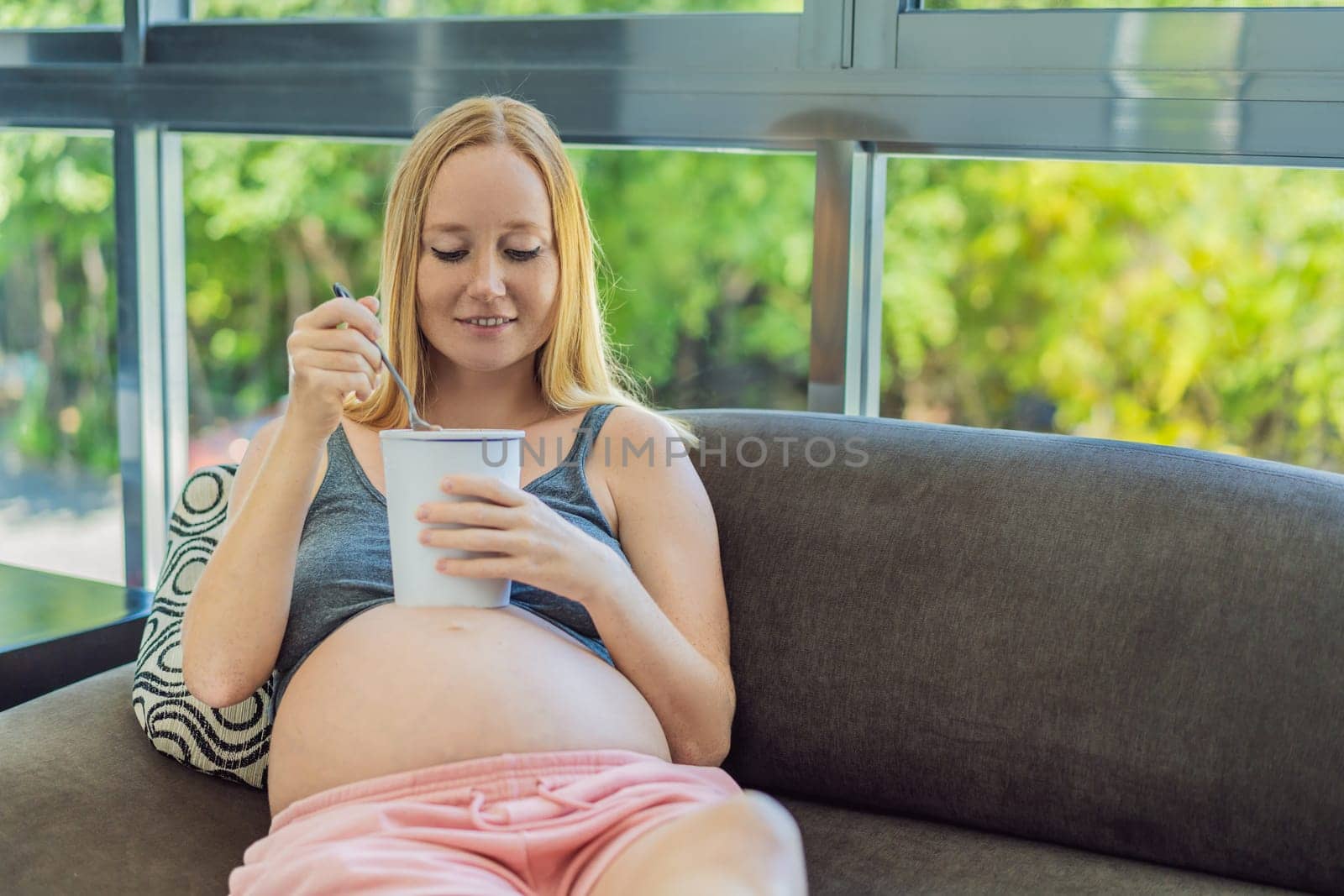 Happy pregnant young woman eating ice cream by galitskaya
