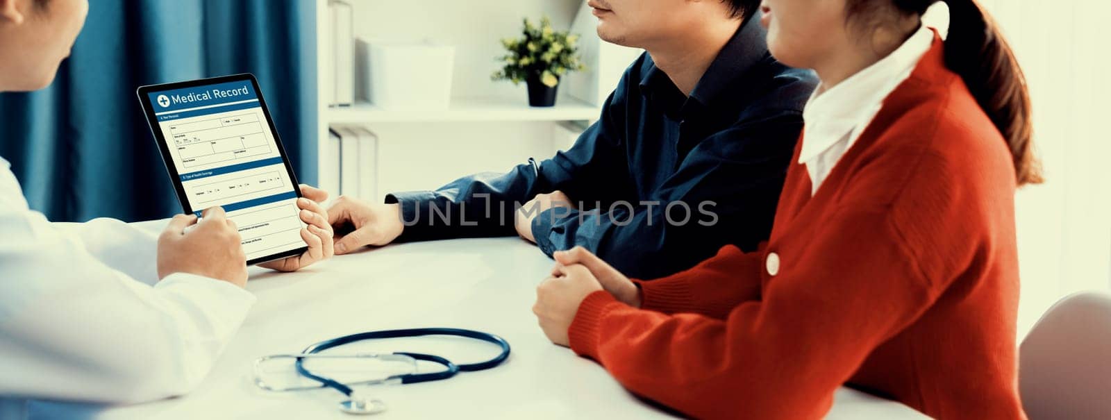 Couple attend fertility consultation with gynecologist at hospital as part family planning care for pregnancy. Loving husband and wife support each other through the doctor appointment. Panorama Rigid