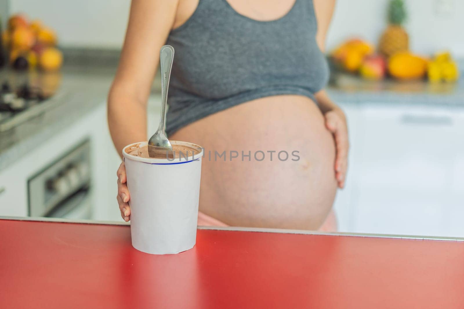 Happy pregnant young woman eating ice cream.