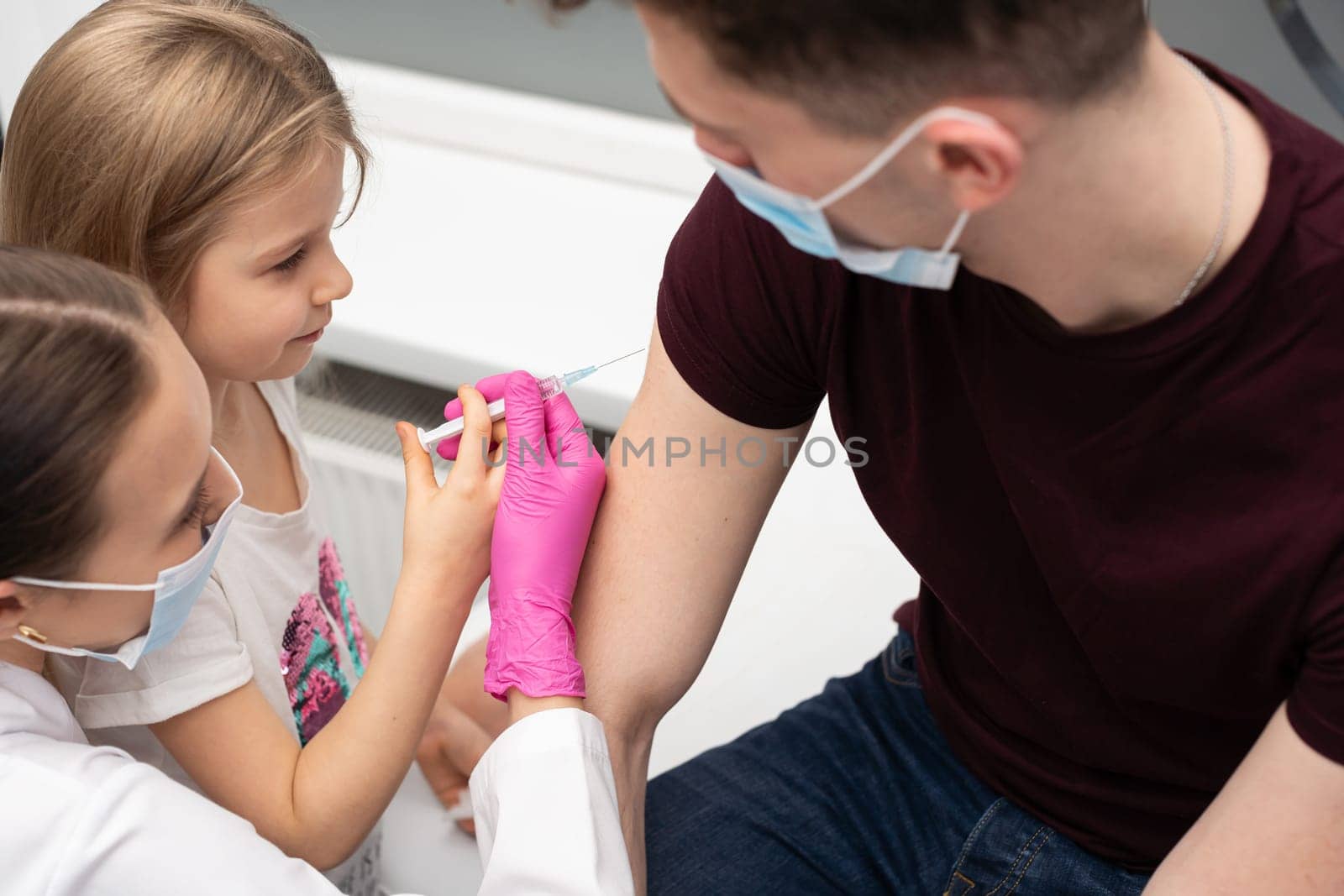 For fun, the nurse shows the girl how to administer the injections. The child performs the vaccine with the help of a nurse. A bold approach to children. Safe vaccination of children.