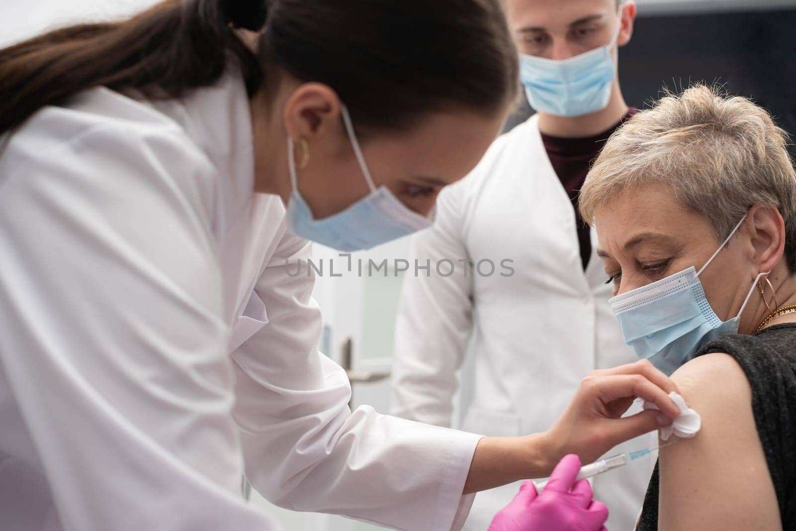 A young nurse injects a woman in her 50s with a new COVID19 vaccine. An injection with a new vaccine to support the body and increase resistance to infectious diseases.