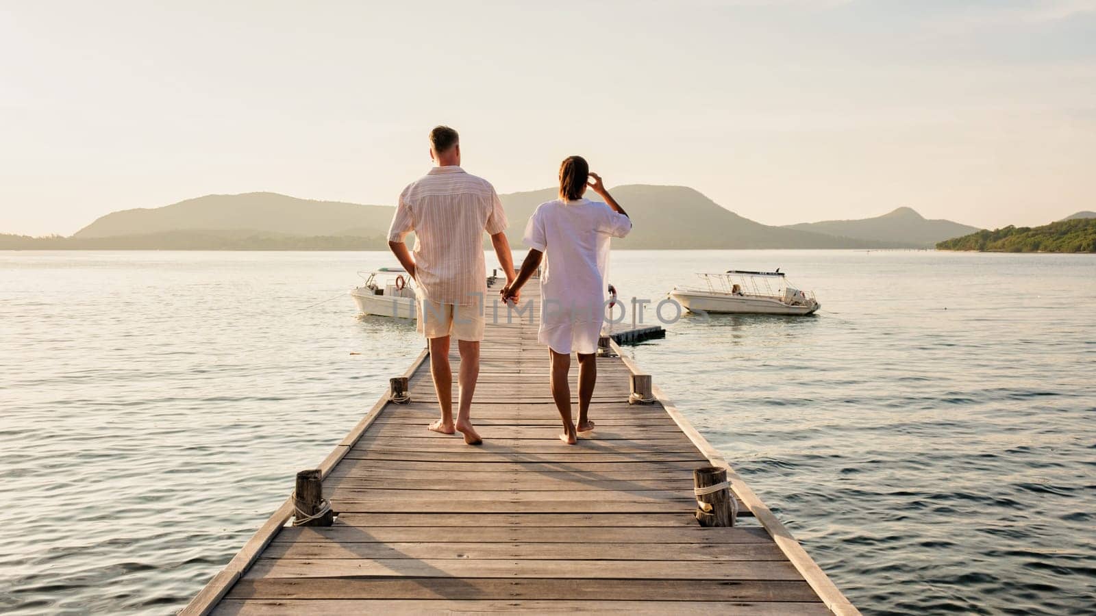 a man and a woman are standing on a dock holding hands by fokkebok