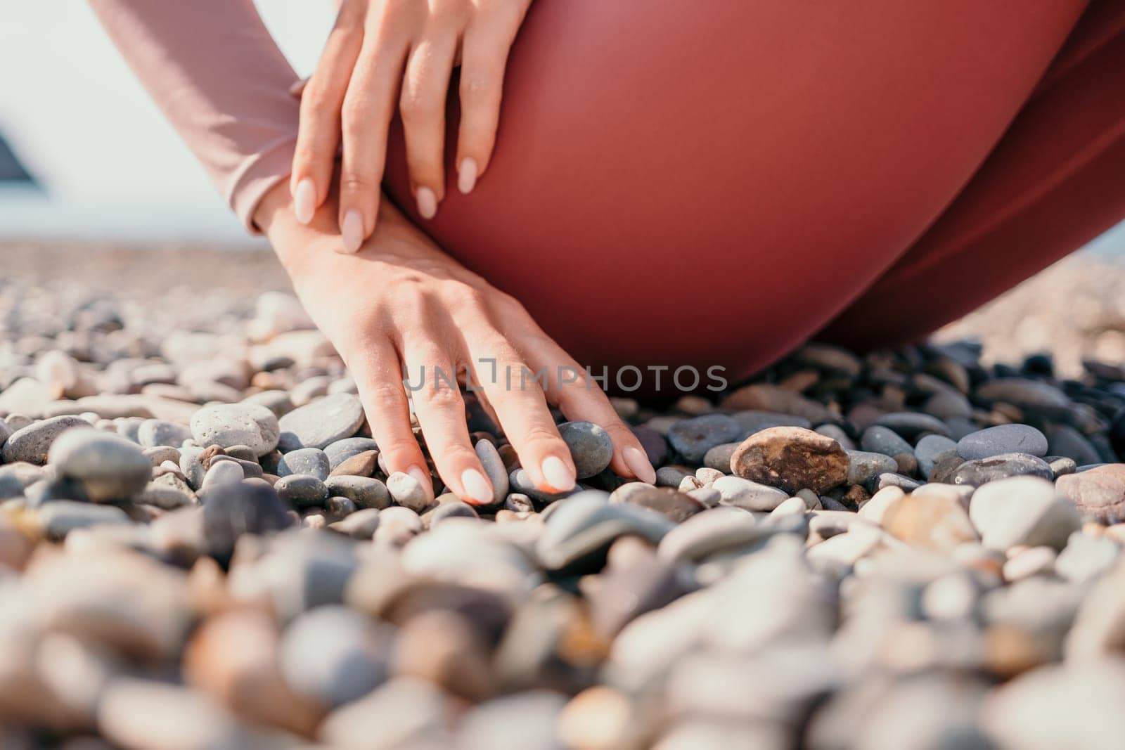 Young woman with long hair in white swimsuit and boho style braclets practicing outdoors on yoga mat by the sea on a sunset. Women's yoga fitness routine. Healthy lifestyle, harmony and meditation