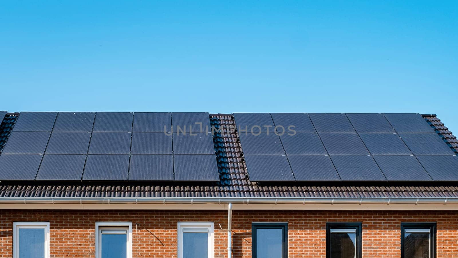 Newly build houses with solar panels attached on the roof against a sunny sky by fokkebok