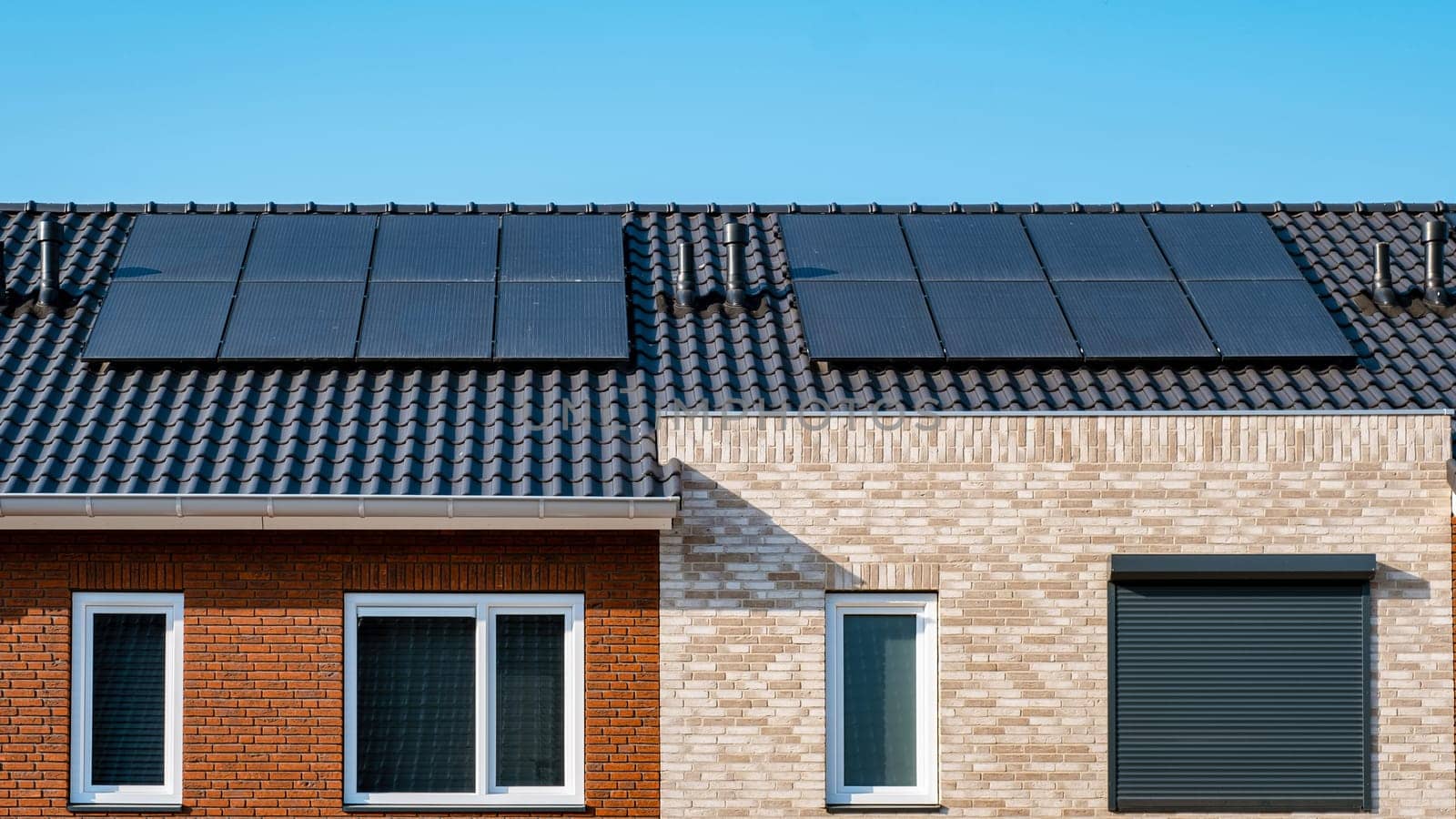 Newly build houses with solar panels attached on the roof against a sunny sky by fokkebok