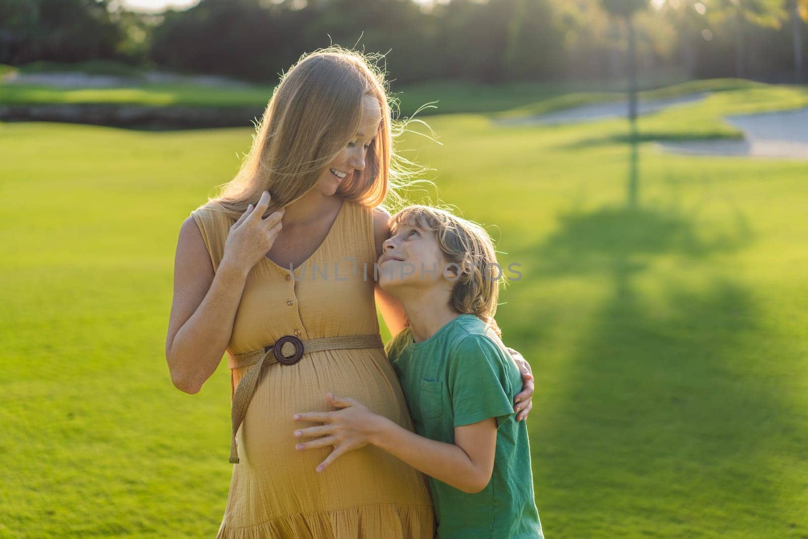 Heartwarming outdoor bonding as a pregnant mom and her son enjoy quality time together, savoring the beauty of nature and creating cherished moments by galitskaya