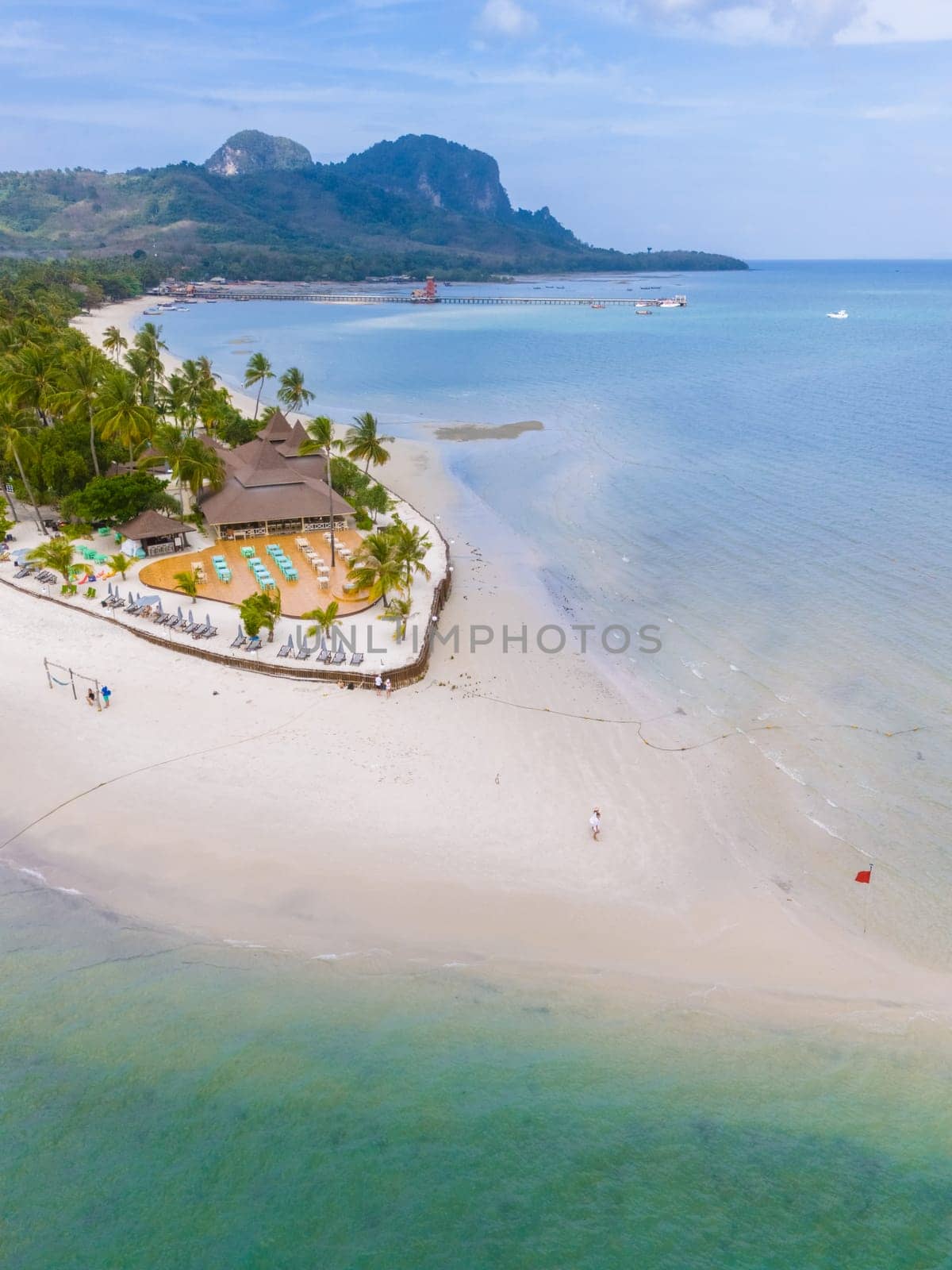 Drone aerial view at Koh Muk a tropical island with palm trees and soft white sand, and a turqouse colored ocean in Koh Mook Trang Thailand