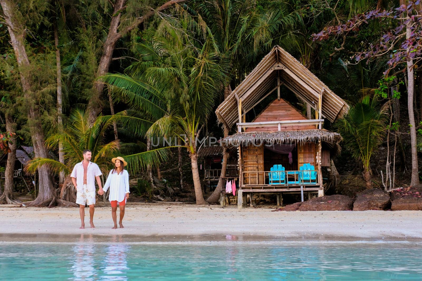 wooden bamboo hut bungalow on the beach. a young couple of men and women on a tropical Island in Thailand relaxing by the ocean at sunset, Koh Wai Island, tropical holiday