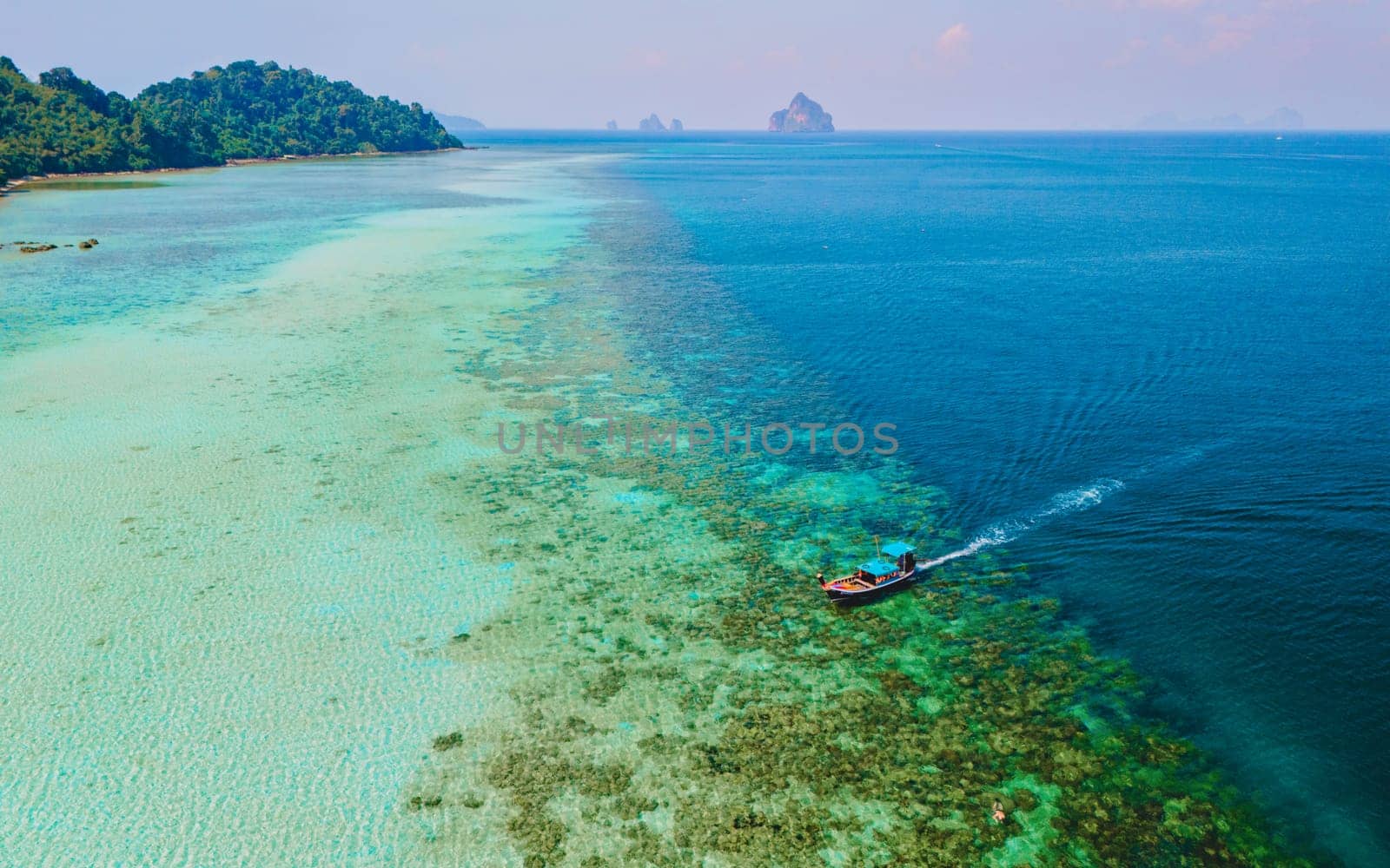 longtail boat in the turqouse colored ocean with clear water at Koh Kradan Thailand by fokkebok