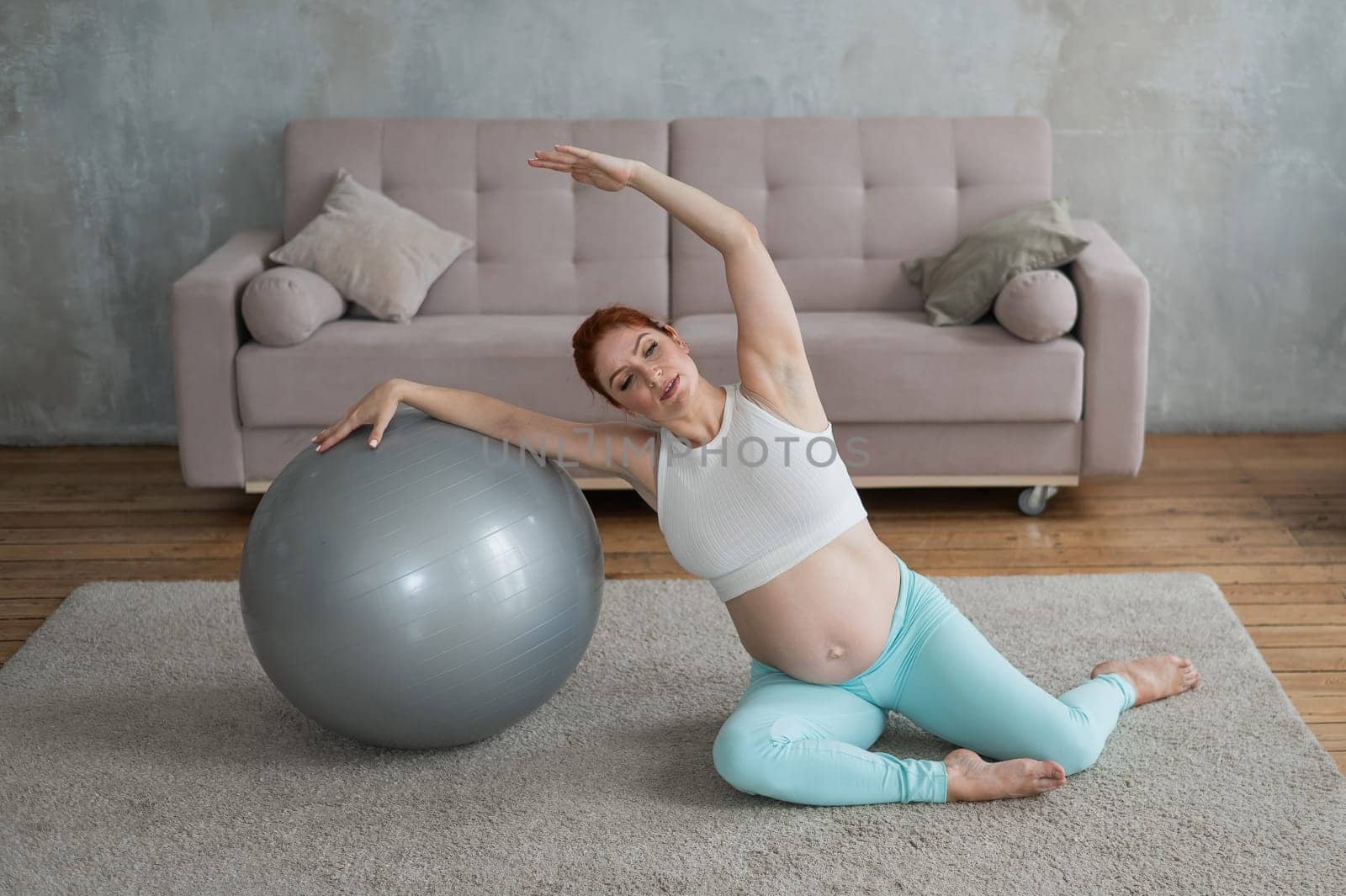 Pregnant woman doing side bends with a fitness ball at home. by mrwed54