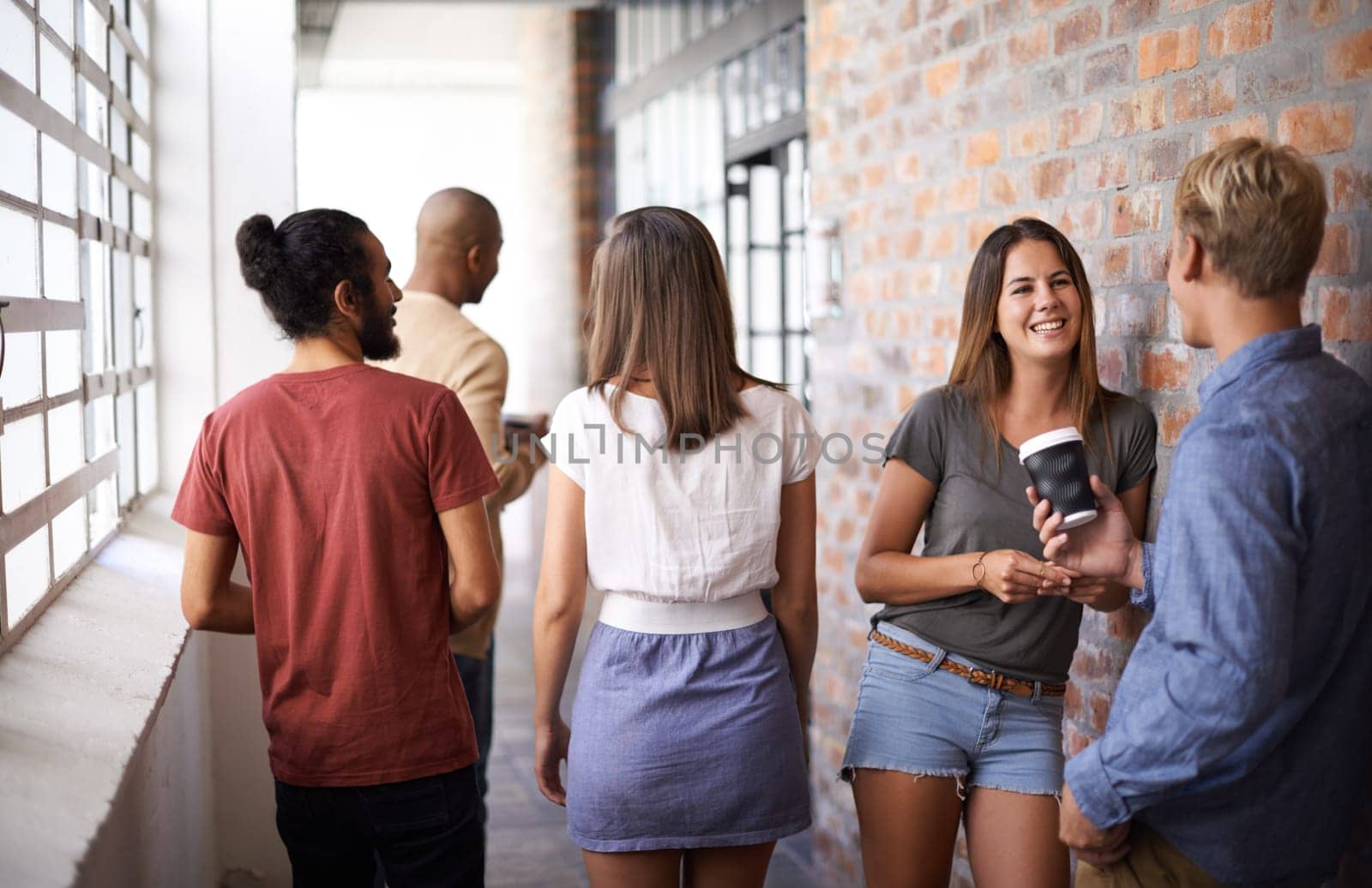 Students, men and women on campus friends, talking and standing together in corridor. Diversity, people and group in college for education, communication and discussion for conversation while smiling.