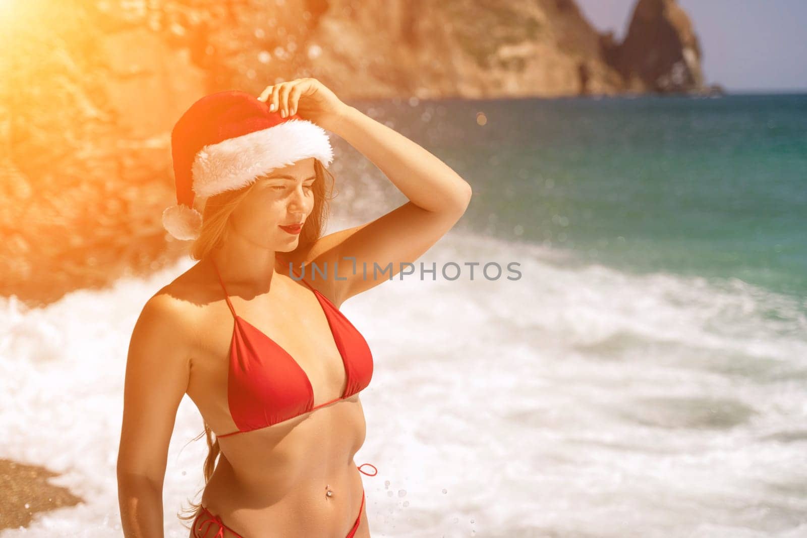 A woman in Santa hat on the seashore, dressed in a red swimsuit. New Year's celebration in a hot country. by Matiunina