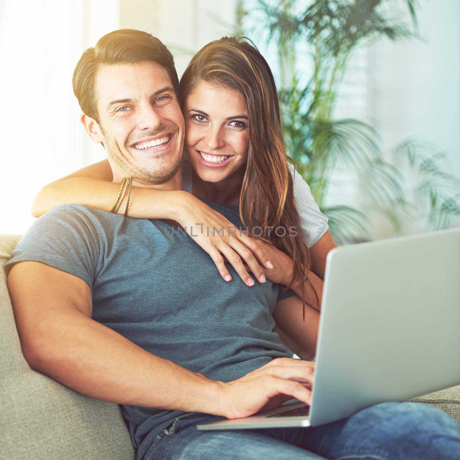 Laptop, smile and woman embrace man on sofa networking on social media, website or internet. Happy, love and female person hugging husband reading online blog with computer in living room at home