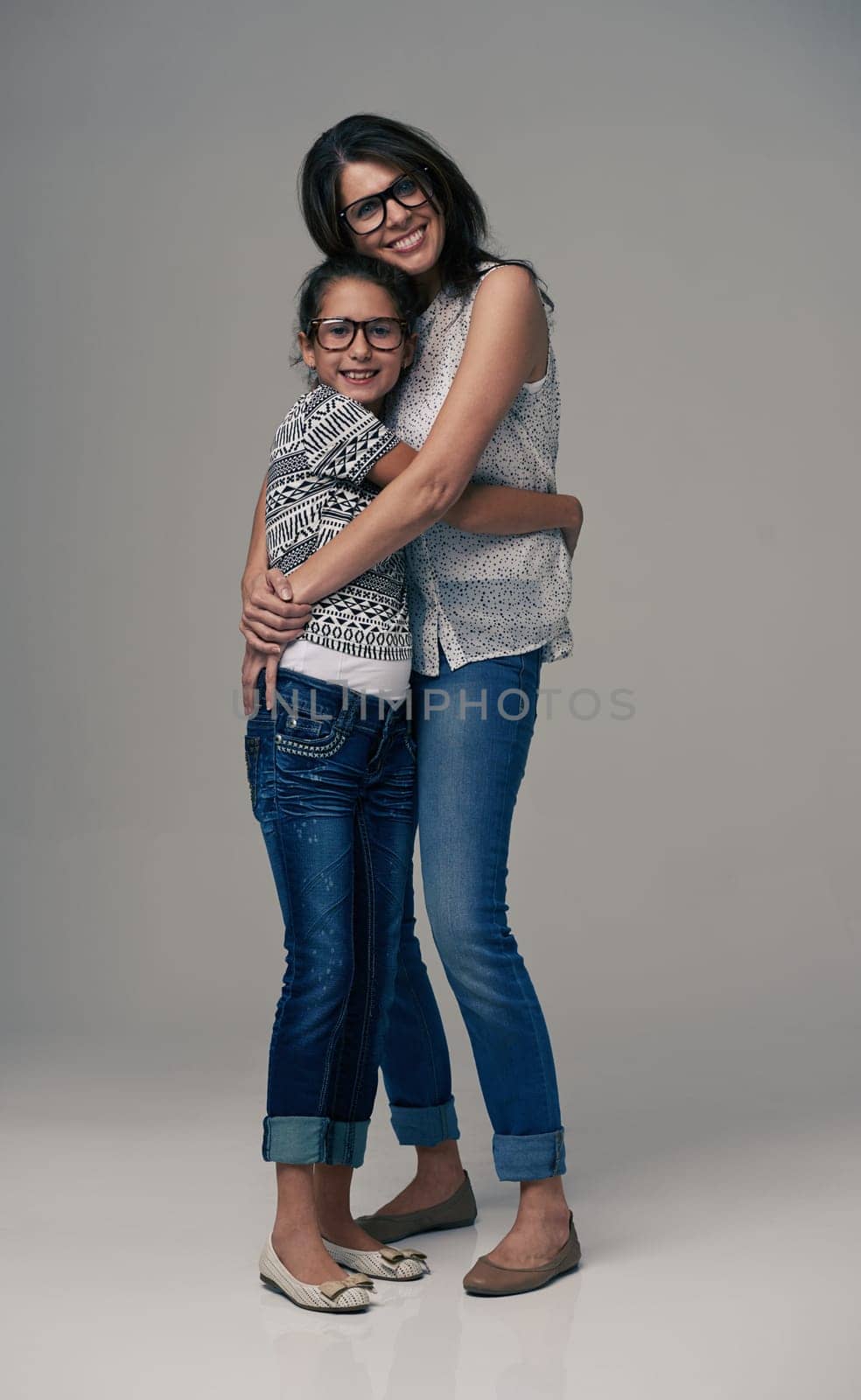 Happy mother, portrait and hugging child with love for care or support in fashion on a gray studio background. Mom, daughter or kid with smile in happiness for parenting or bonding on mockup space.