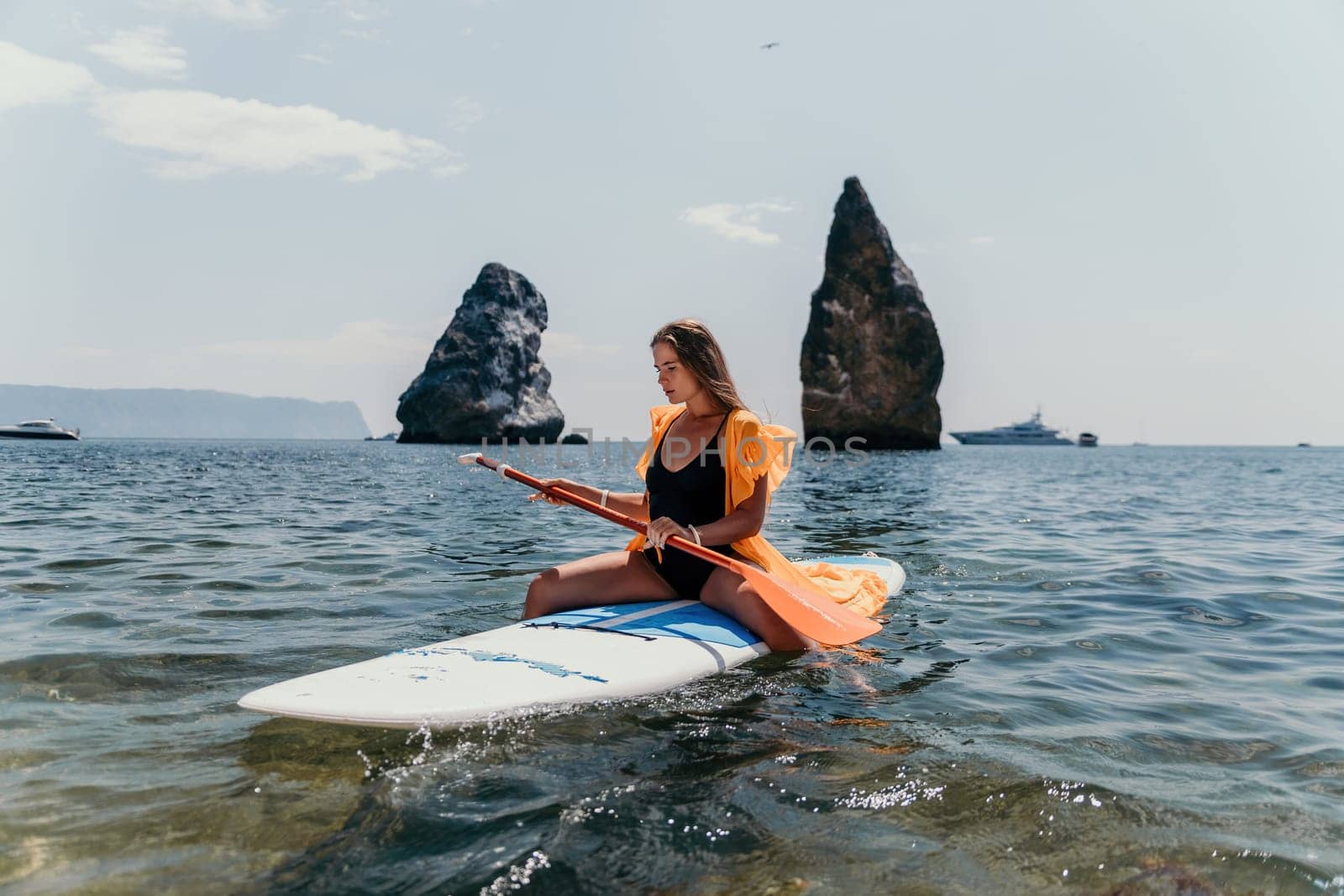 Woman sea sup. Close up portrait of happy young caucasian woman with long hair looking at camera and smiling. Cute woman portrait in bikini posing on sup board in the sea by panophotograph