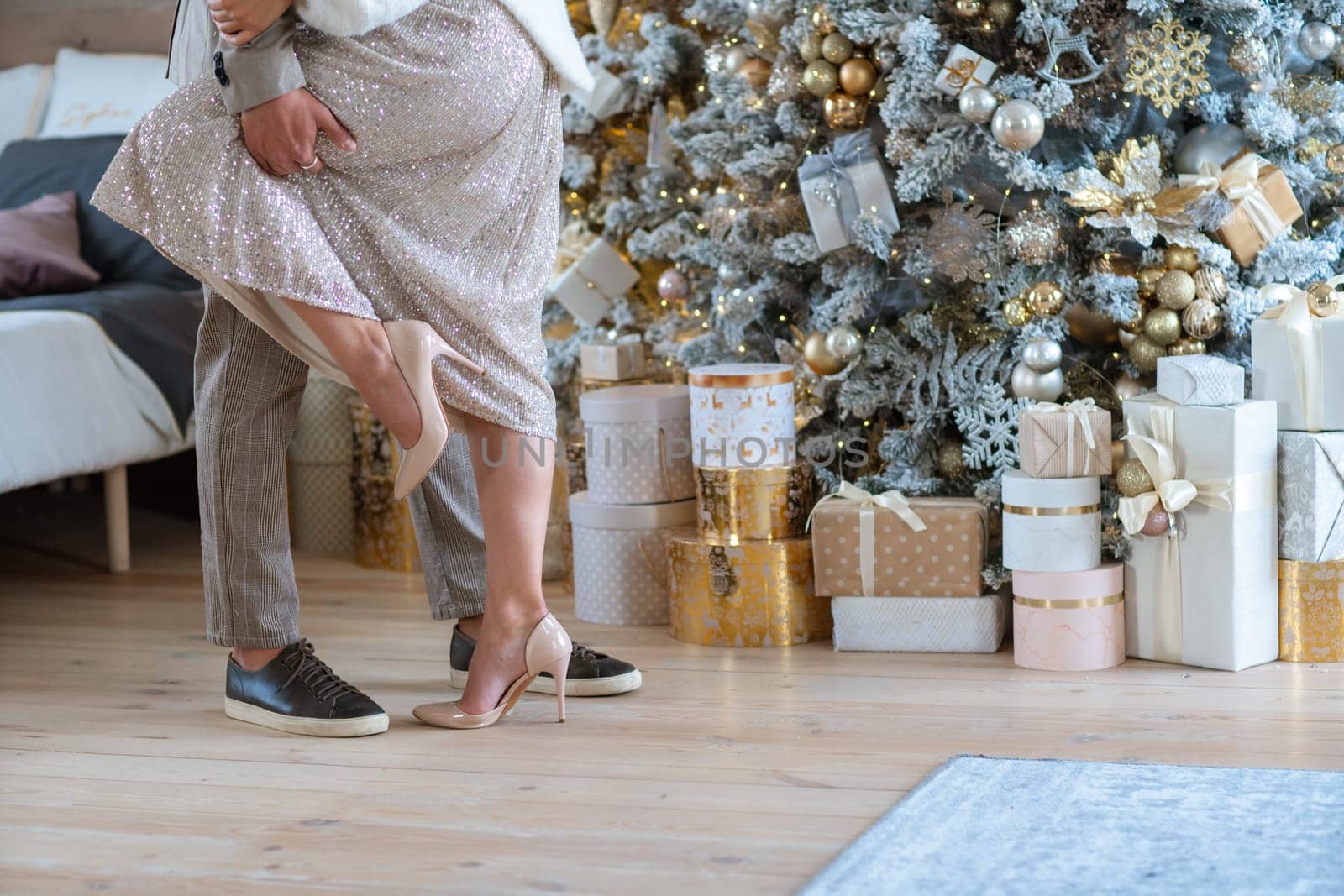 Romantic couple standing near Christmas tree at home and hugging.