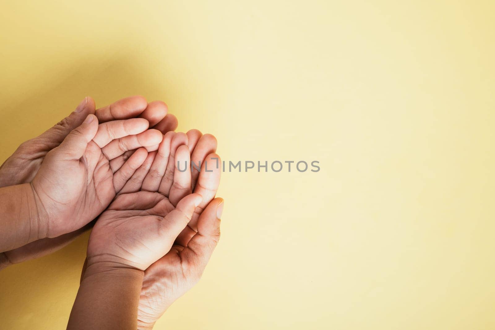 Studio shot, Close-up top view of family hands stack on isolated background. Parents and child hold empty space together representing Family and Parents Day. by Sorapop