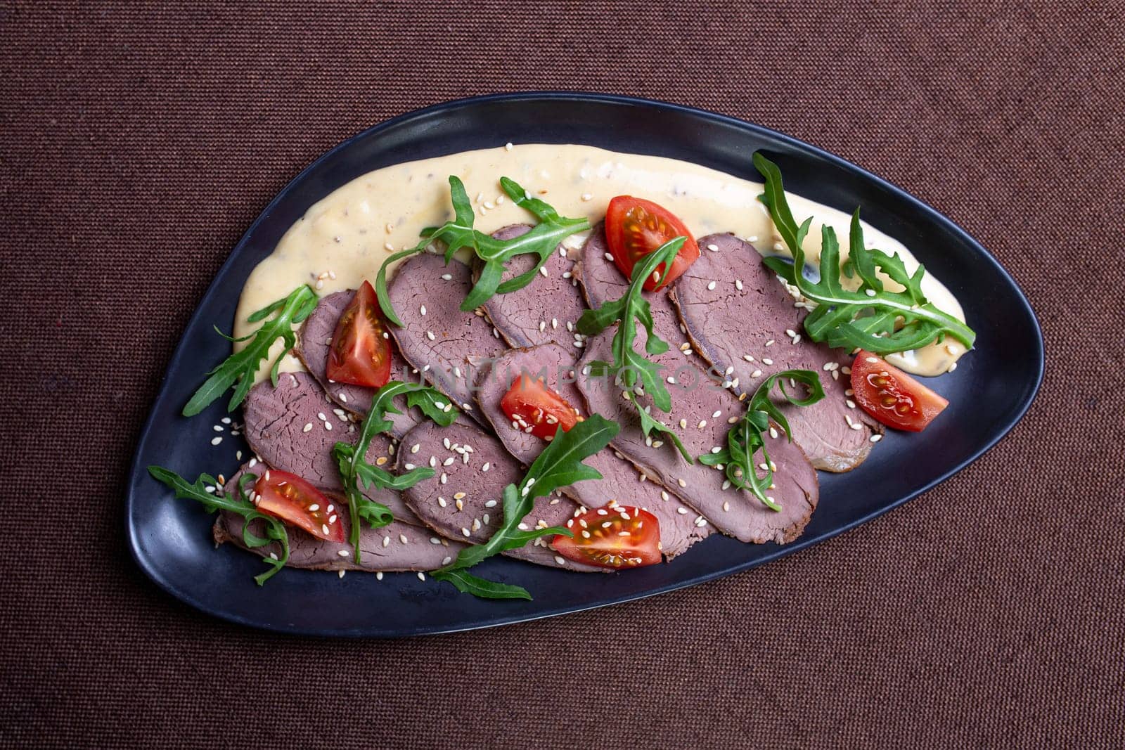 Duck breast with arugula, cherry tomatoes, and sesame seeds on a creamy sauce by Pukhovskiy