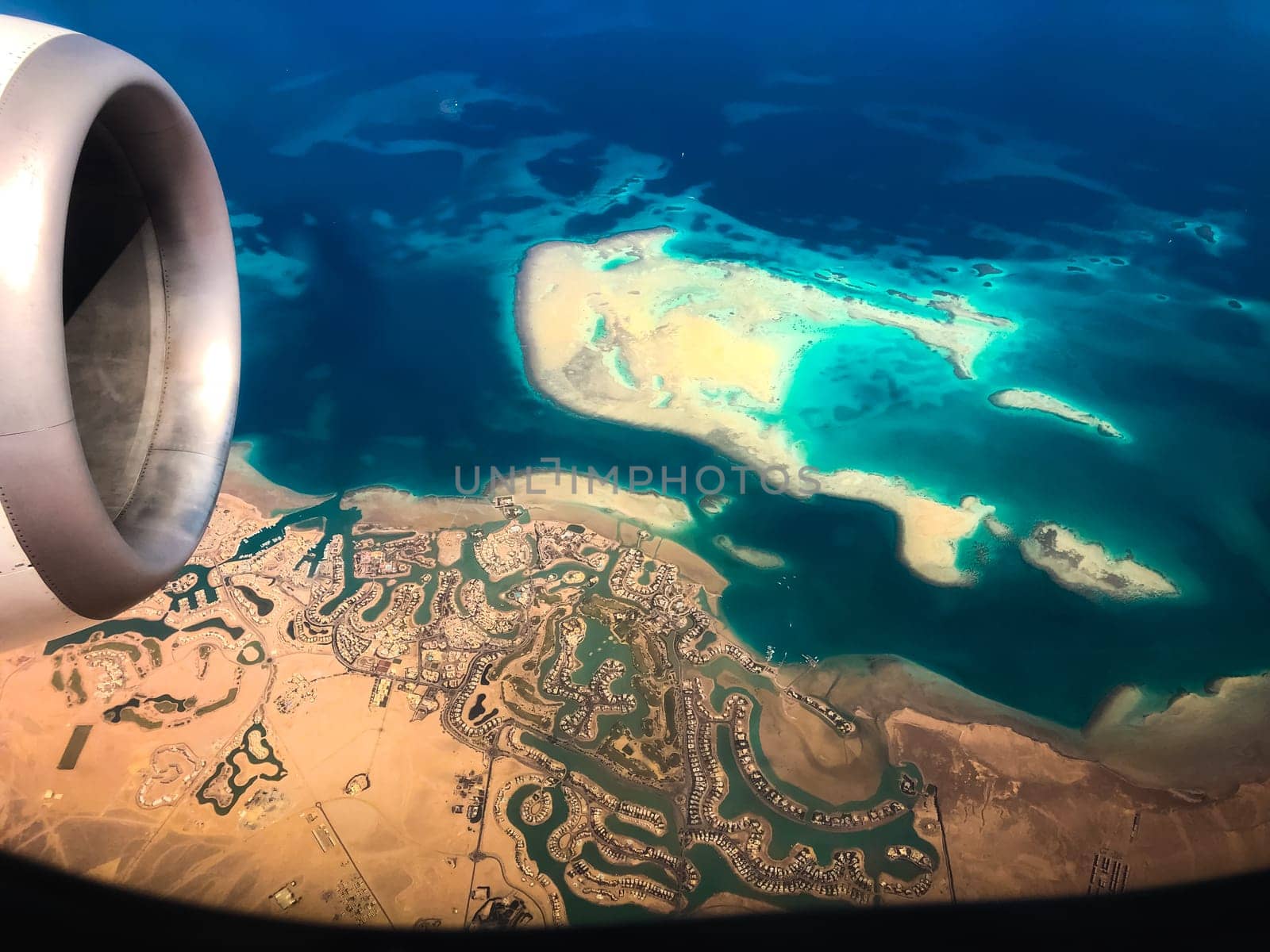 Aerial top view from airplane coastline Egyptian Desert islands. Red sea Sharm Al Sheikh Egypt. Amazing shoot bird eye plane window mountains. Travel concept. turbine aircraft engine flying over ocean