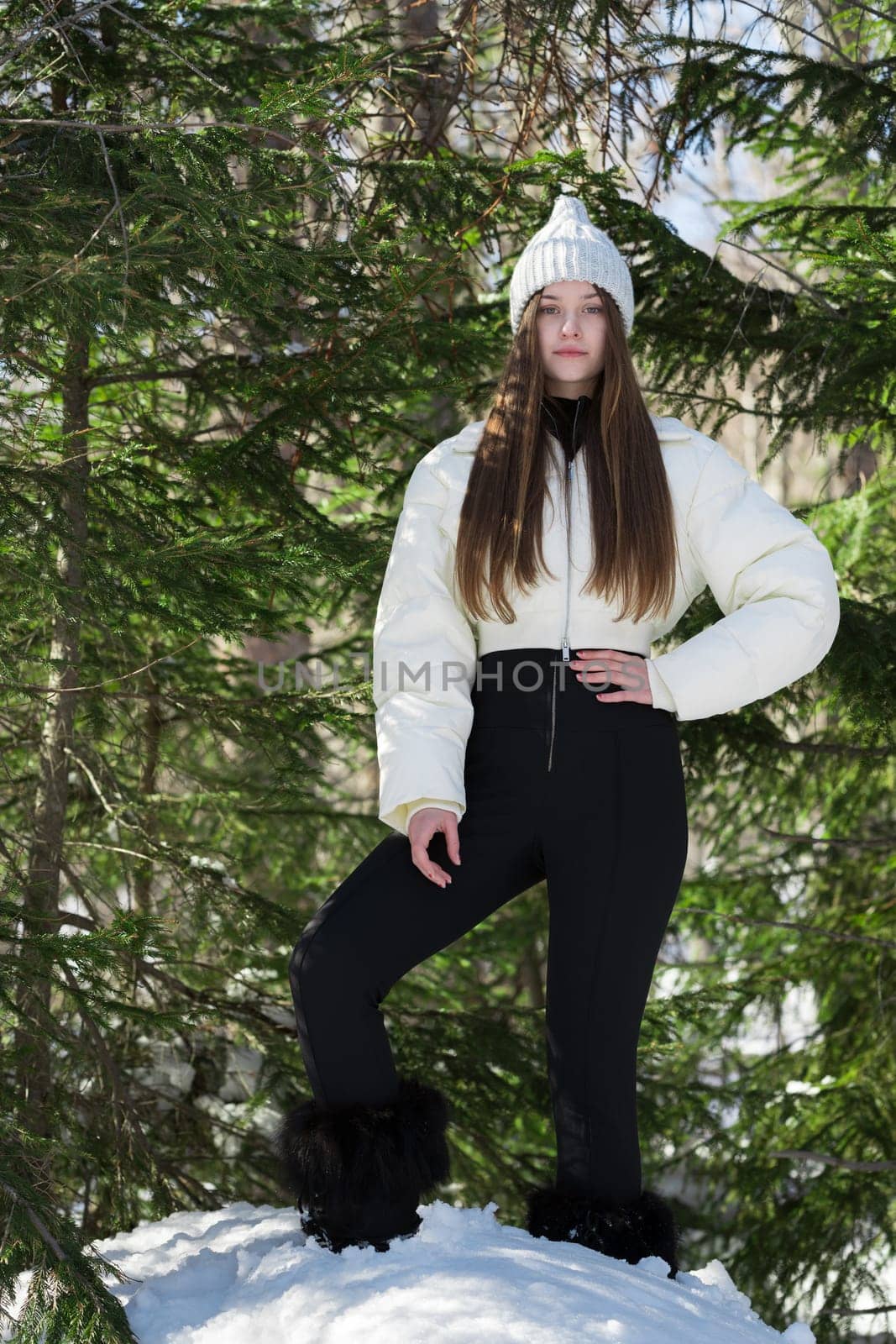 Serene teenager girl standing in winter pine woodland, looking at camera. Full length female model by Alexander-Piragis