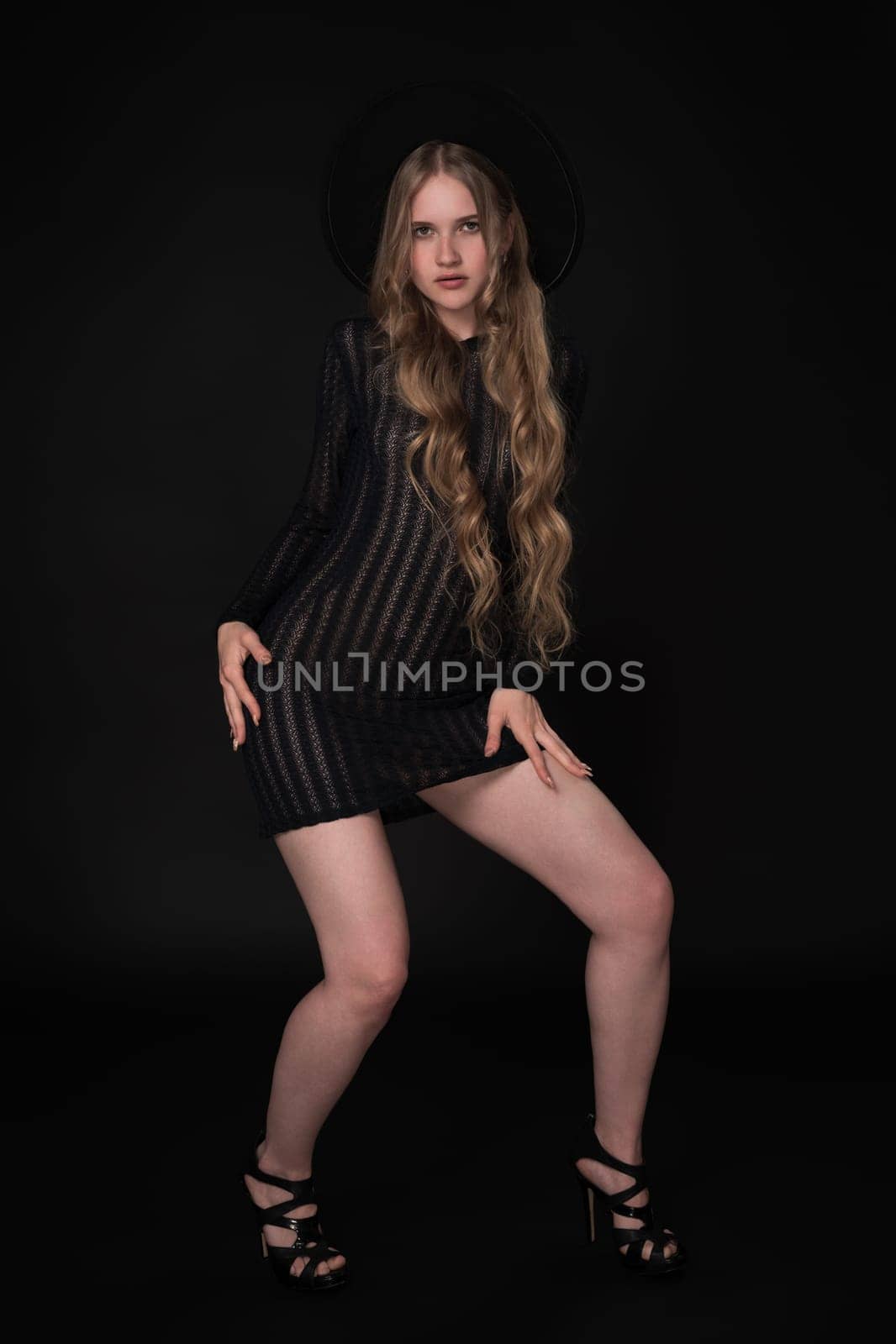 Woman with long legs in short knitted transparent dress, wide-brimmed felt hat and high-heeled shoes by Alexander-Piragis